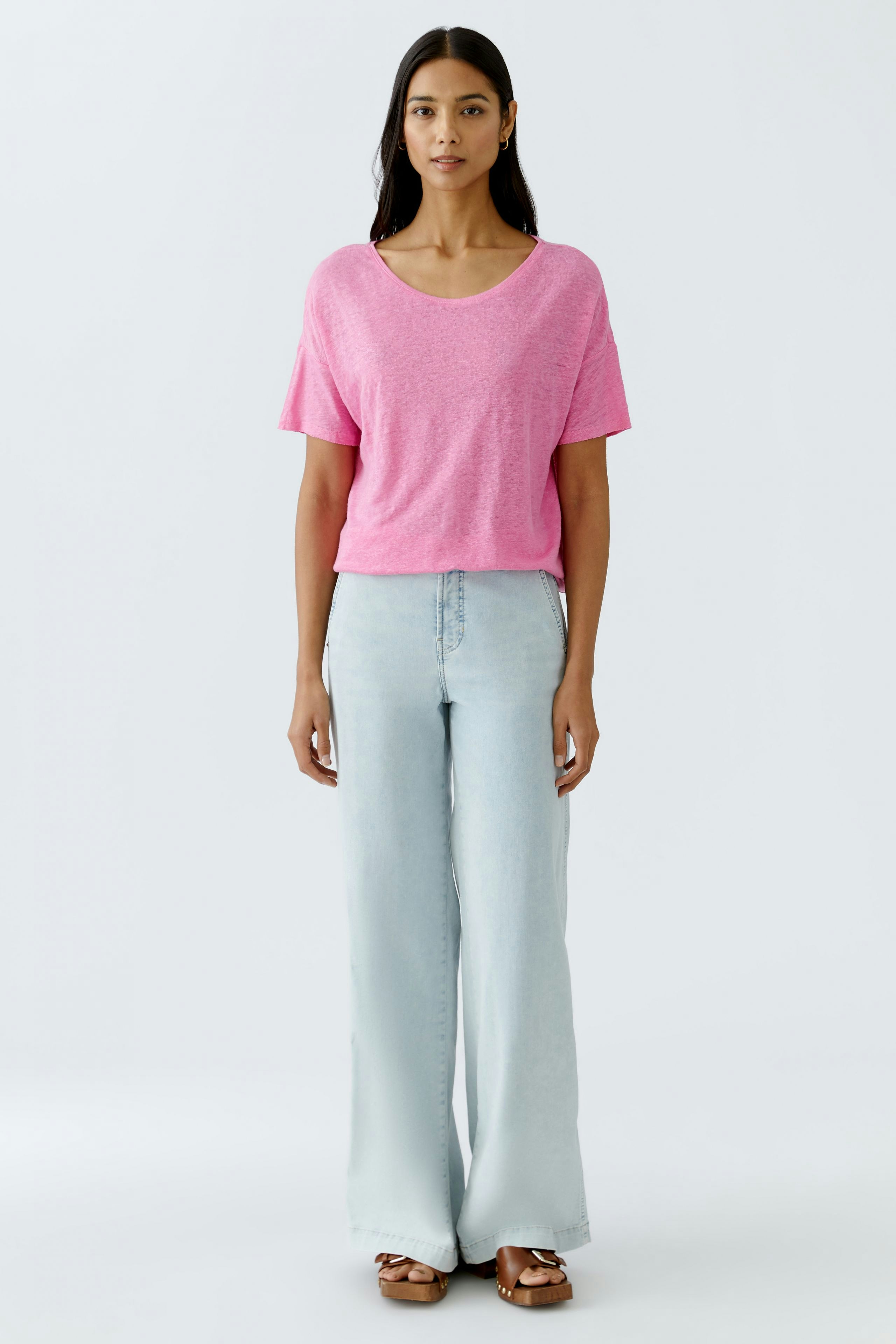 Leichtes Damen-T-Shirt in Pink: Frau trägt lässiges, lockeres Shirt mit V-Ausschnitt und weiten Jeans.