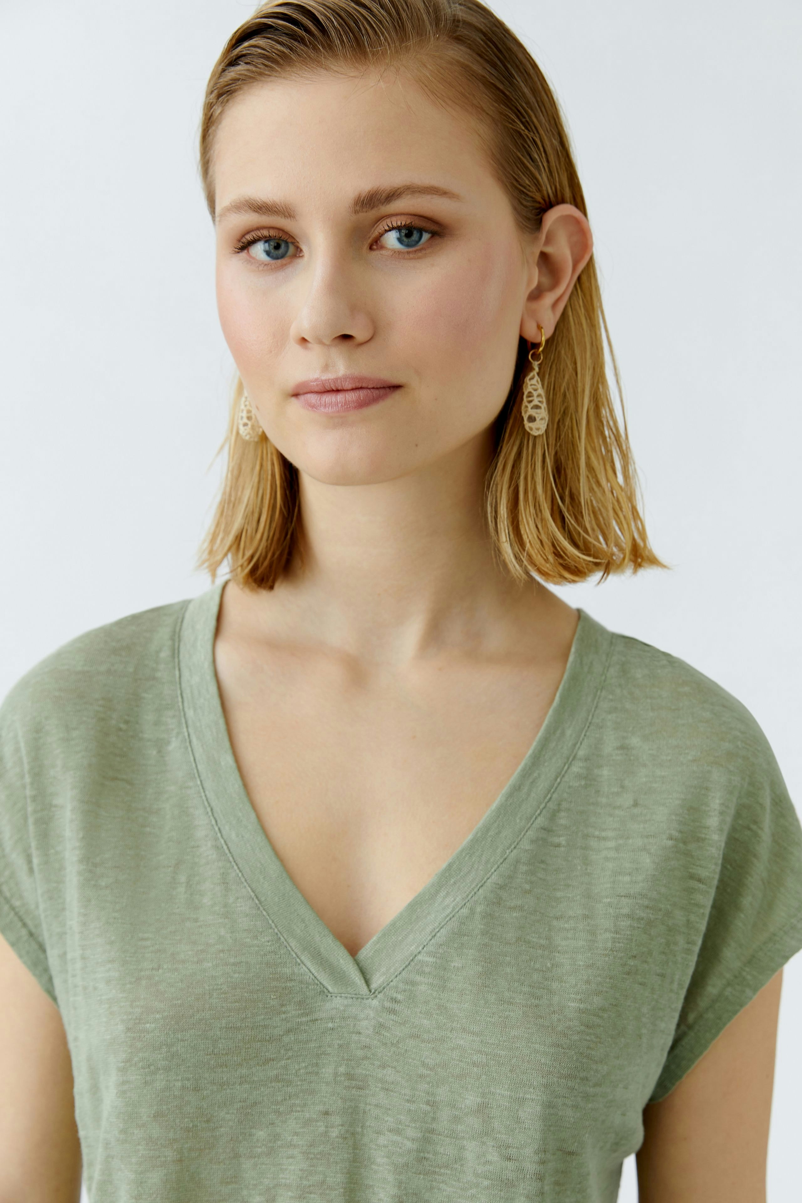 Damen-T-Shirt: Junge Frau in einem lässigen, hellgrünen V-Ausschnitt-Shirt mit kurzen Ärmeln.