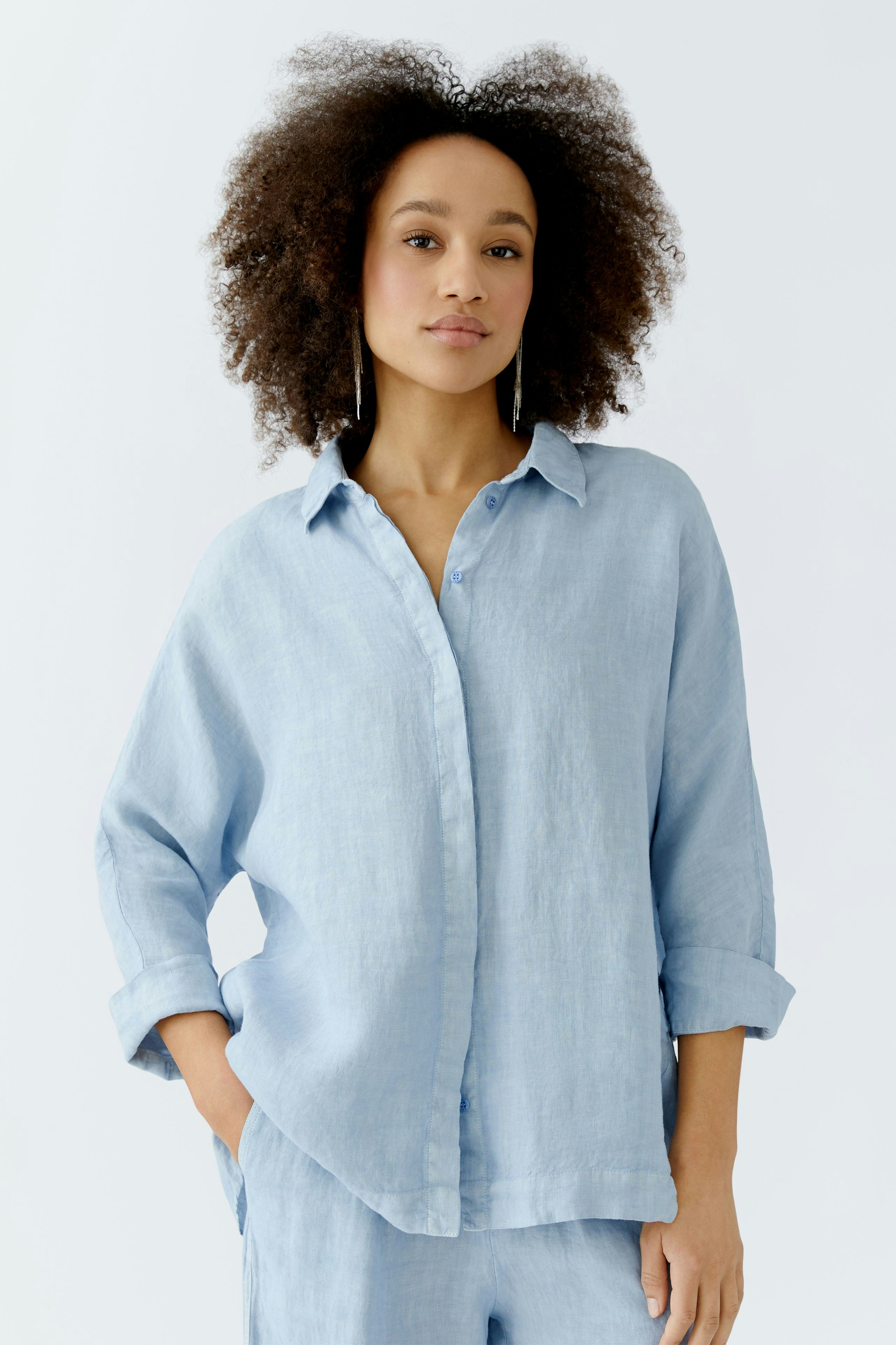 Light blue blouse: Woman in a relaxed-fit, button-up blouse with rolled sleeves, exuding casual style.