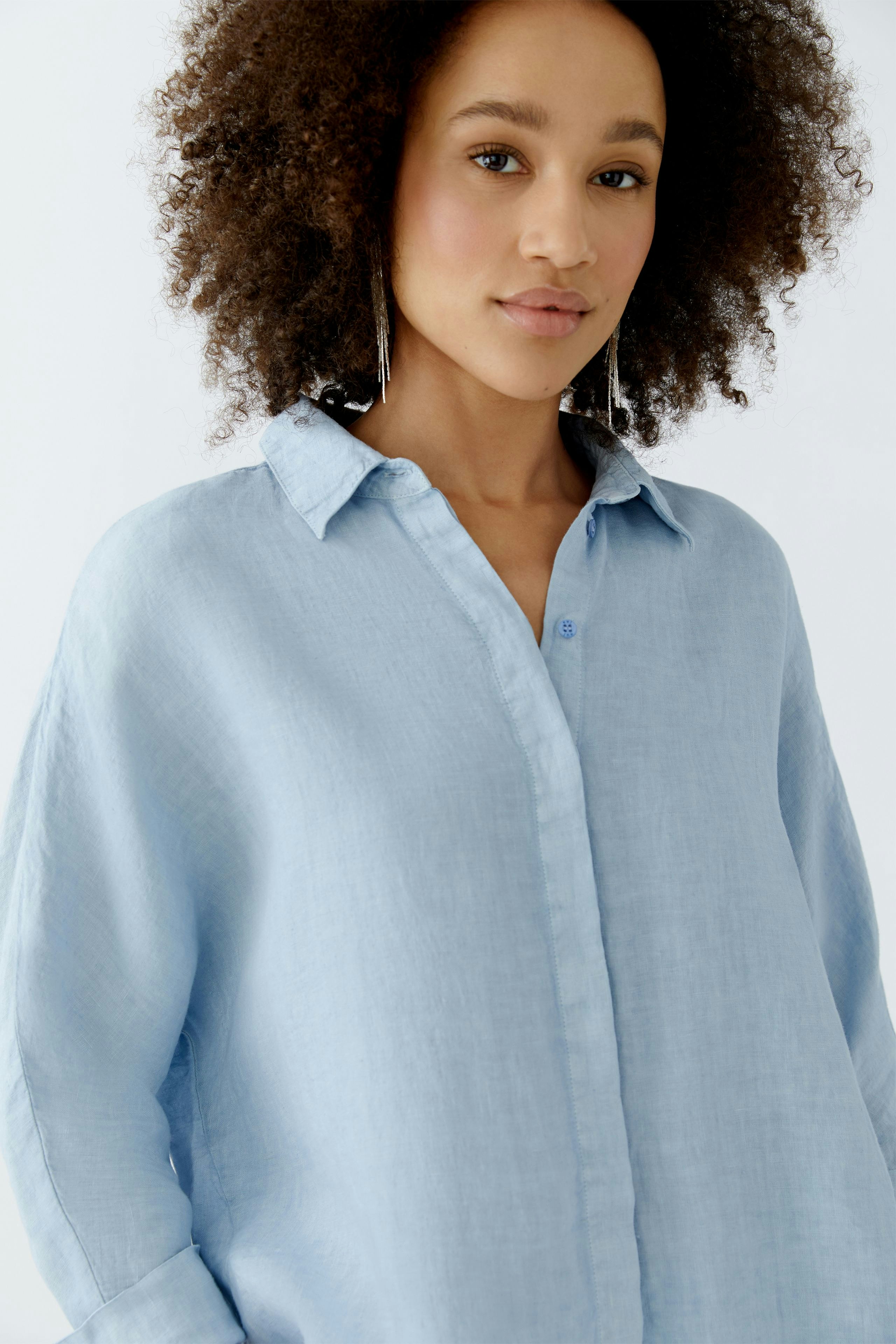 Light blue blouse: Woman in a relaxed-fit, button-up shirt with a soft texture.