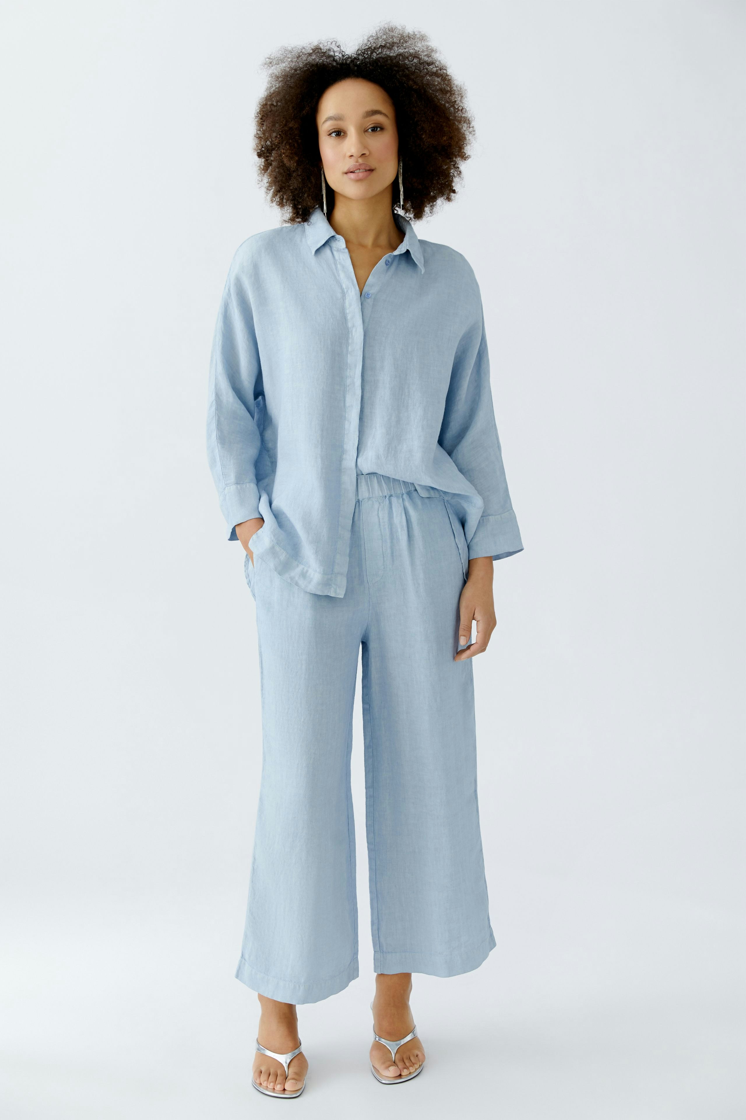 Light blue blouse: Woman in a relaxed fit shirt with a collar and wide sleeves.