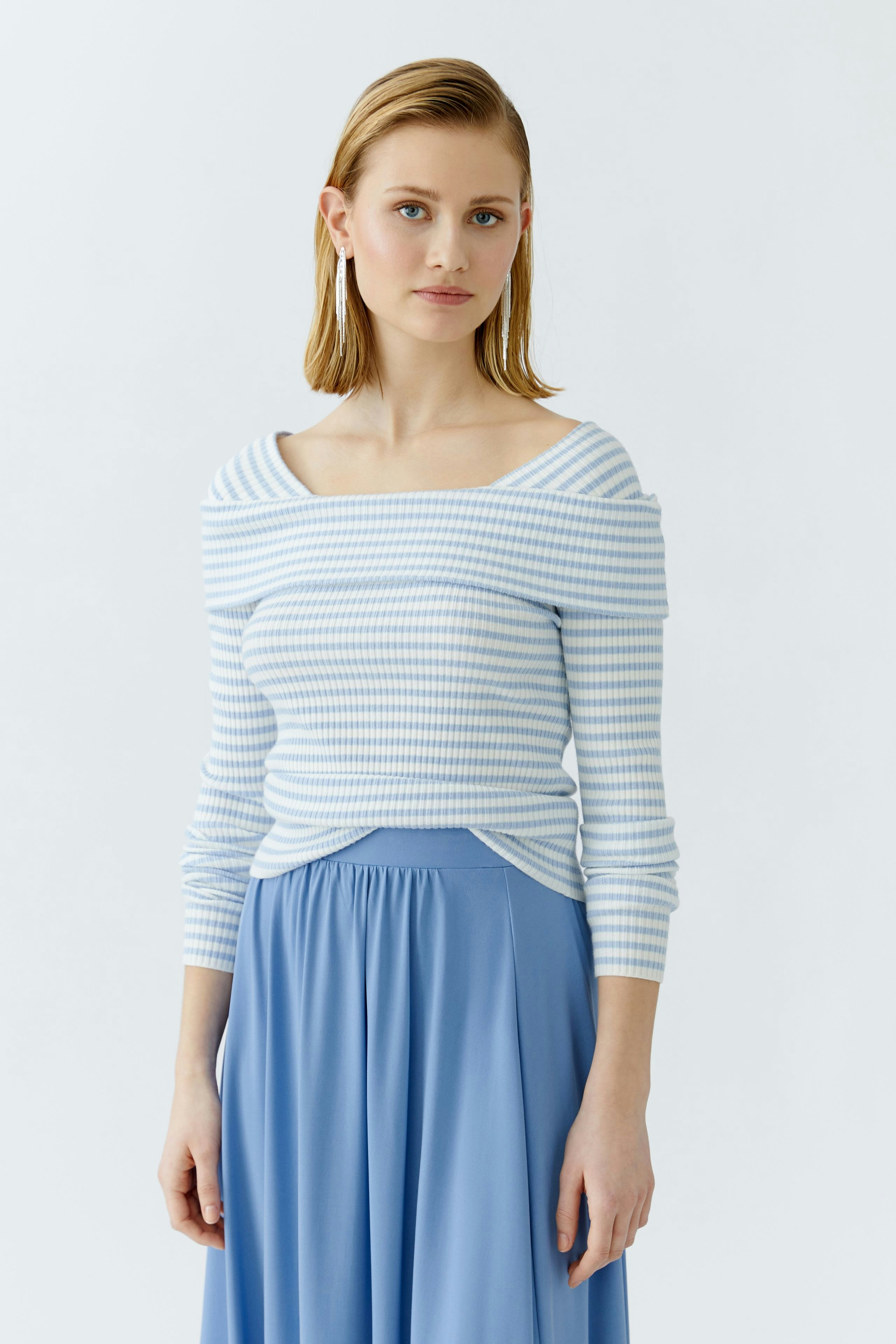 Casual women's pullover: Young woman in a light blue striped pullover paired with a flowing skirt.