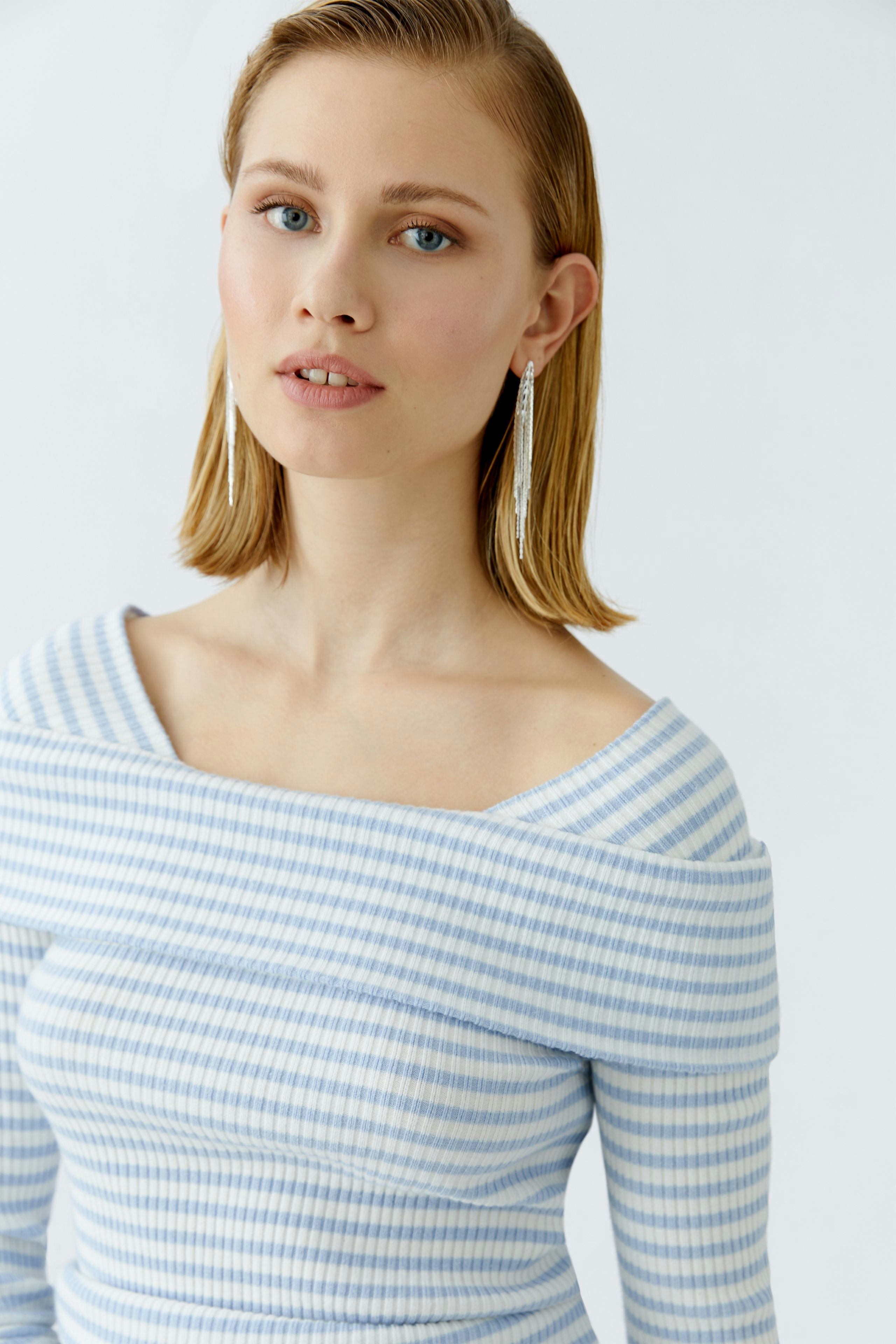 Casual women's pullover: Young woman in a light blue striped pullover with an off-shoulder design.