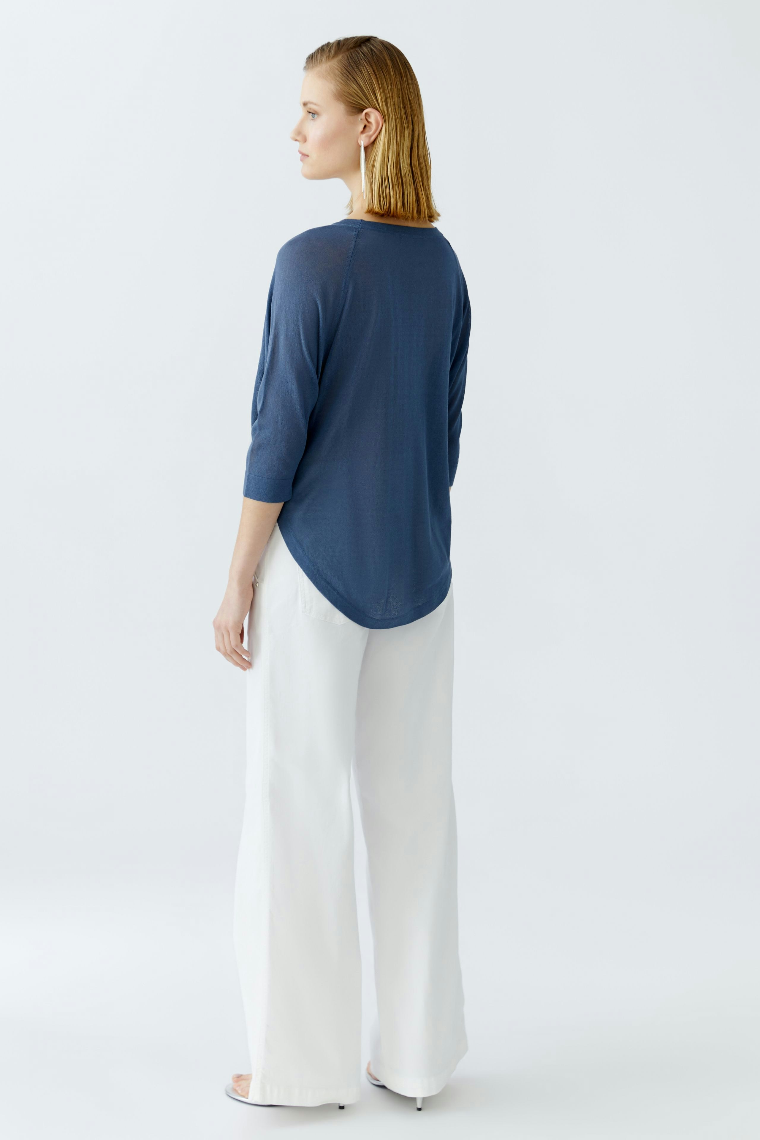 Damen-Pullover: Frau in blauem, lässigem Pullover mit 3/4-Ärmeln und Rundhalsausschnitt von hinten.