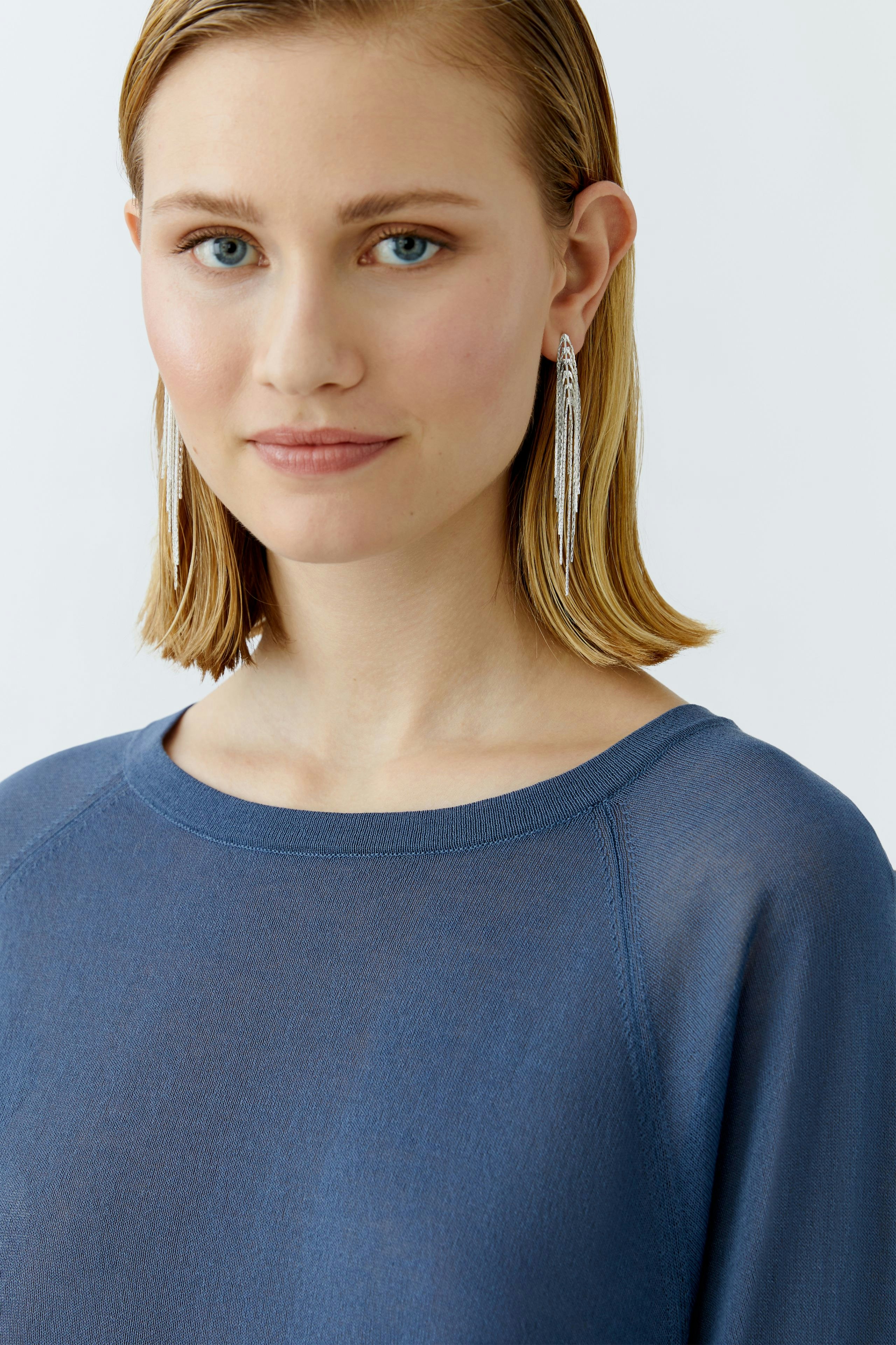 Damen-Pullover: Junge Frau in einem blauen, lässigen Pullover mit Rundhalsausschnitt und kurzen Ärmeln.