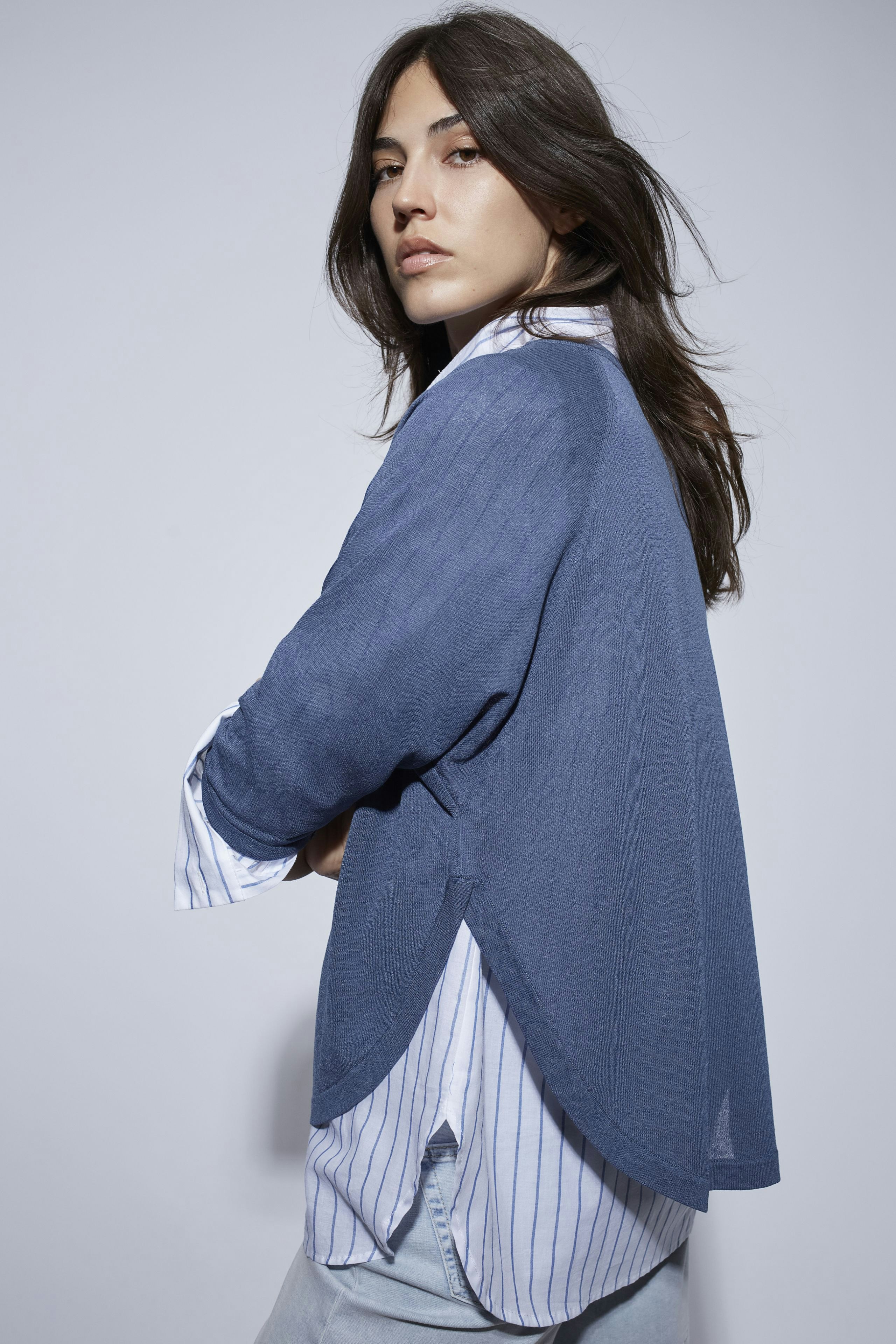 Damen-Pullover: Frau in blauem, lässigem Pullover mit gestreifter Bluse, entspannt und modern.
