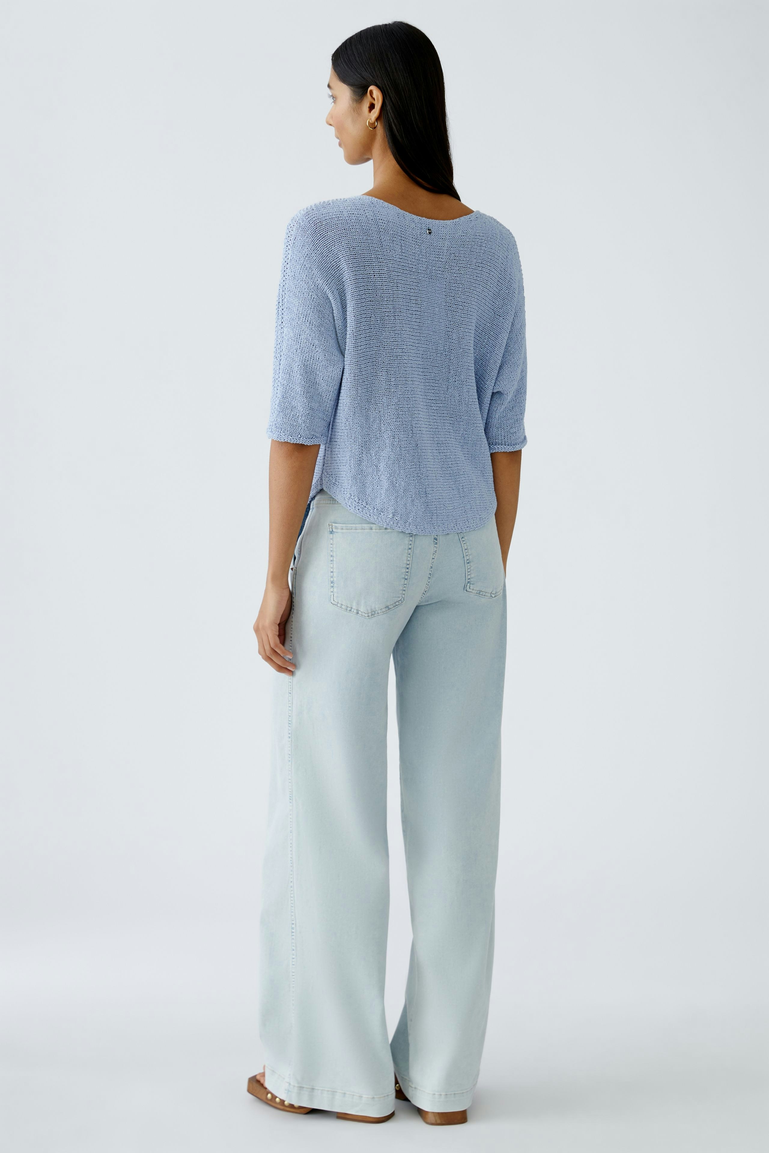 Stylish women's pullover: A woman in a light blue pullover with a relaxed fit, paired with wide-leg jeans.