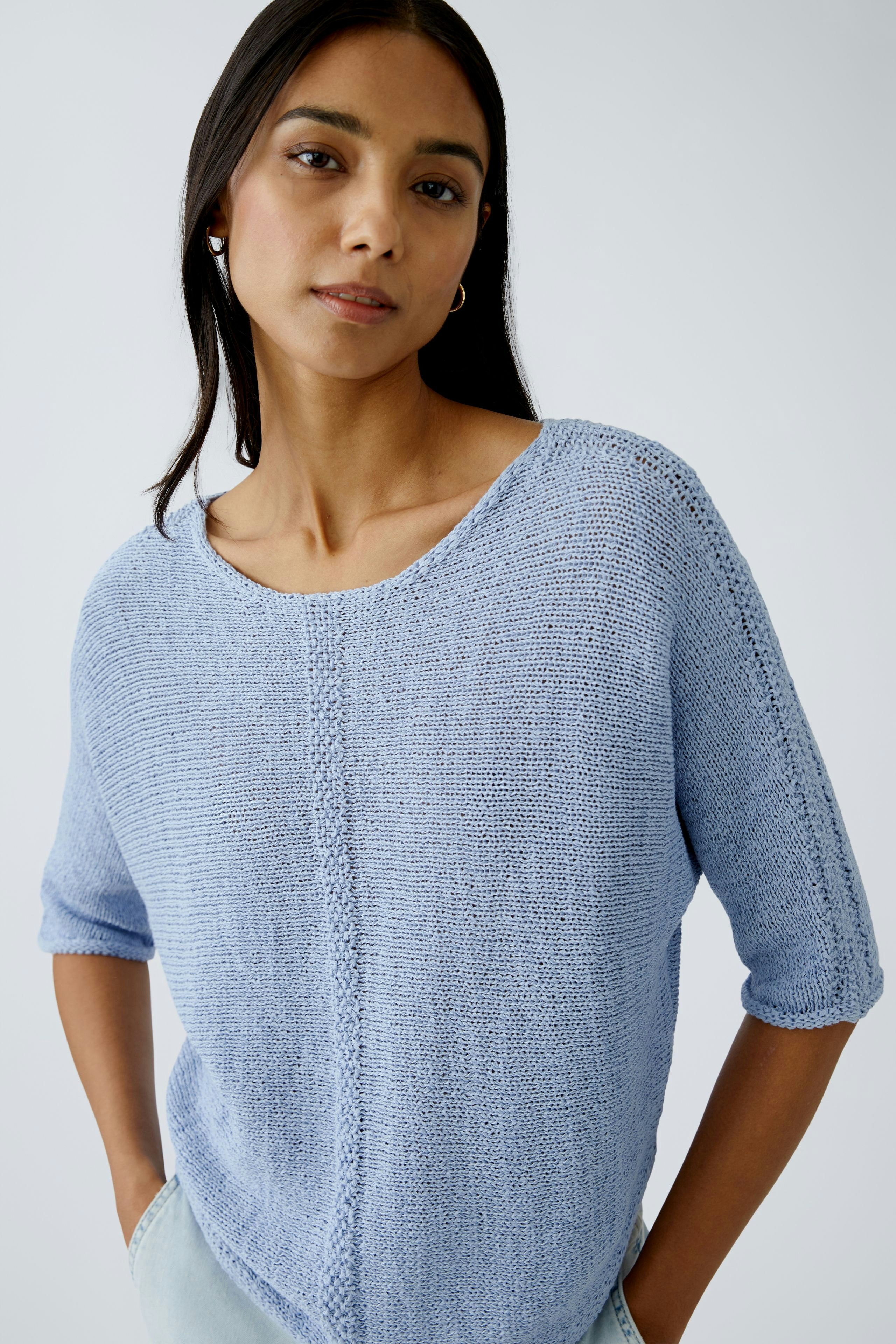 Stylish women's pullover: A woman in a light blue knitted pullover with a relaxed fit.