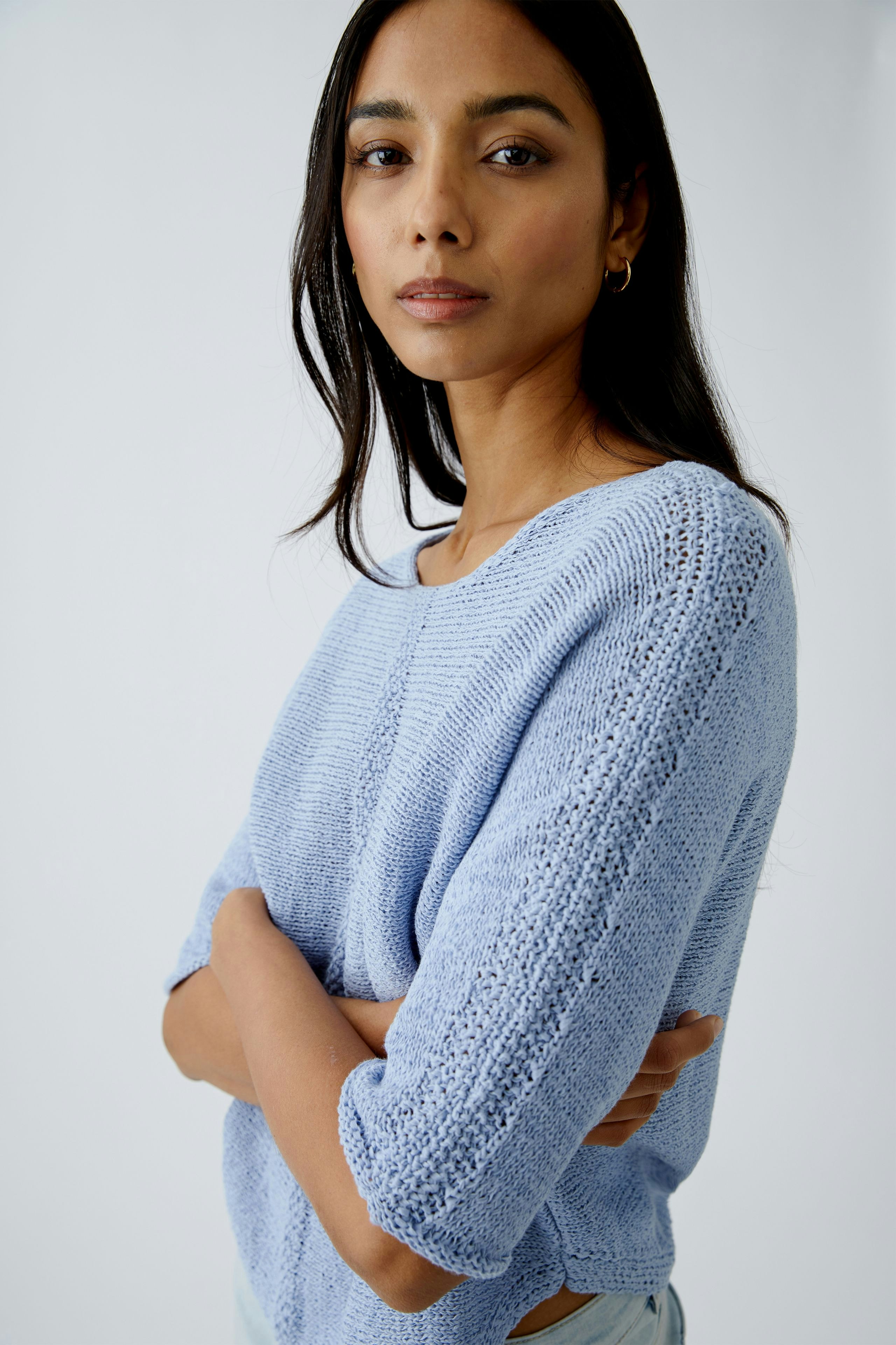 Stylish women's pullover: A woman in a light blue knitted pullover with a relaxed fit.