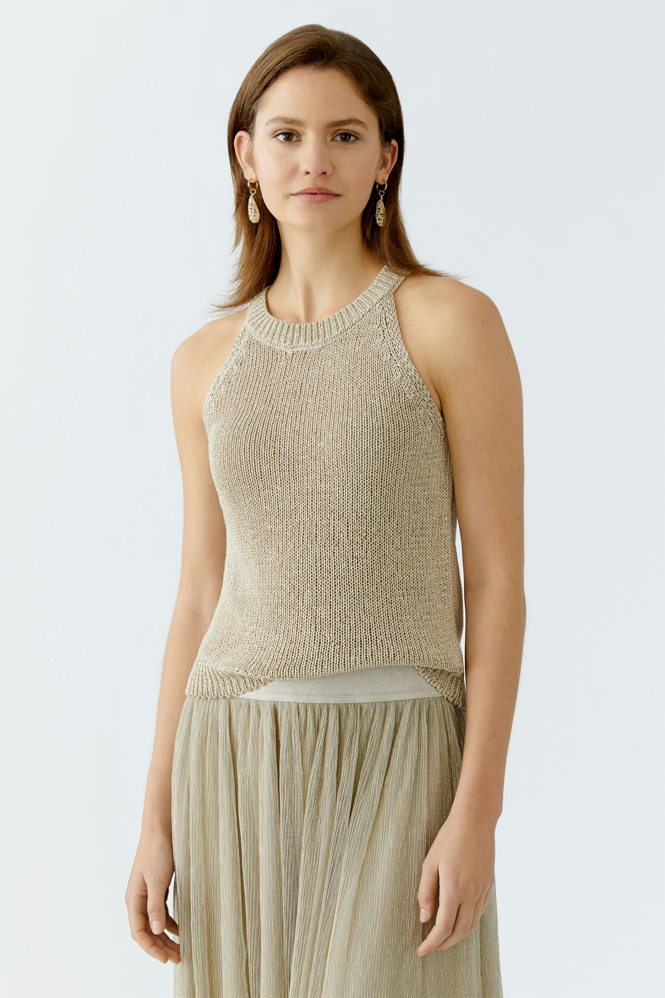 Stylish women's top: A woman in a beige knitted pullover, paired with a flowing skirt, exudes elegance.