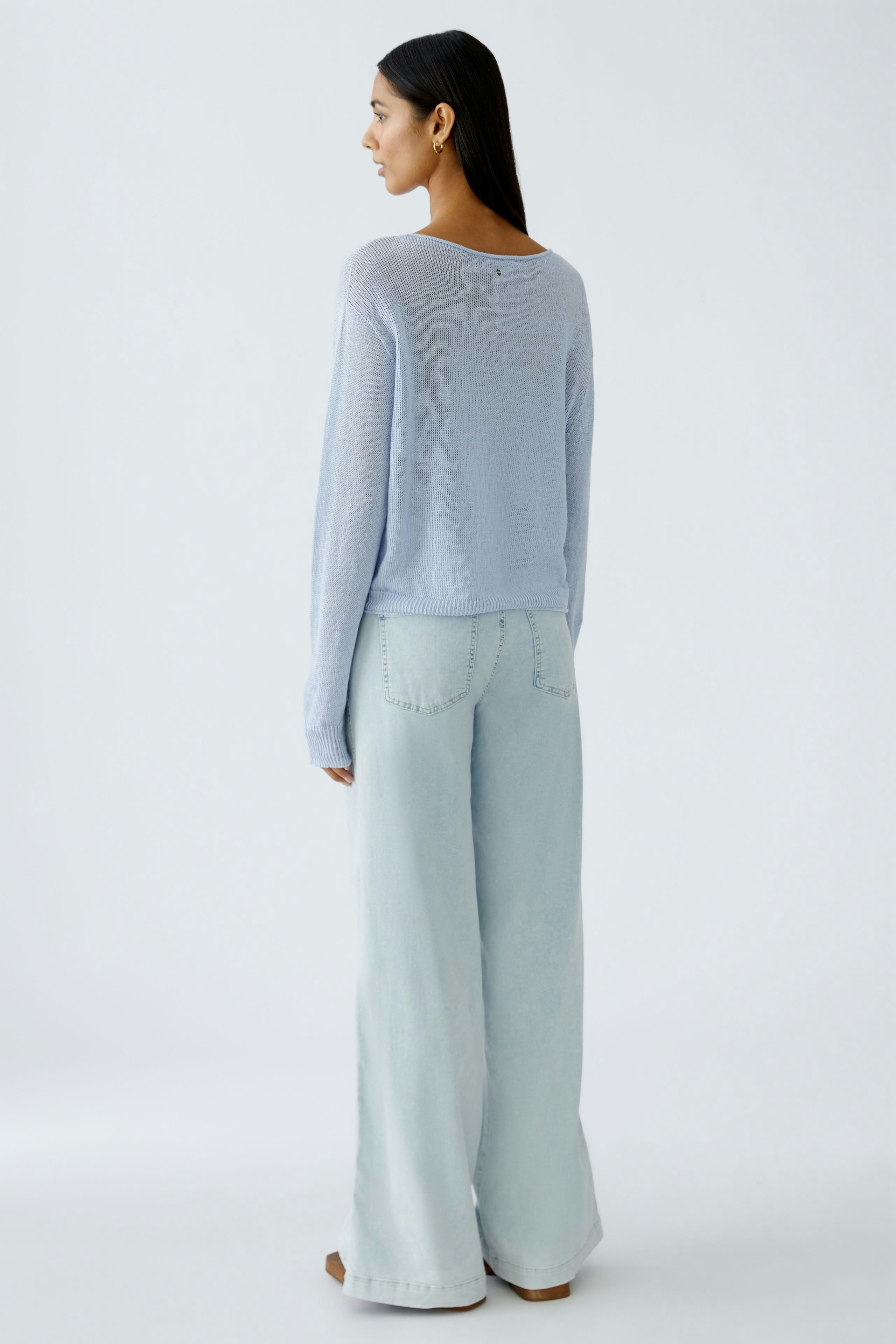 Stylish women's pullover: A woman in a light blue pullover paired with wide-leg jeans.