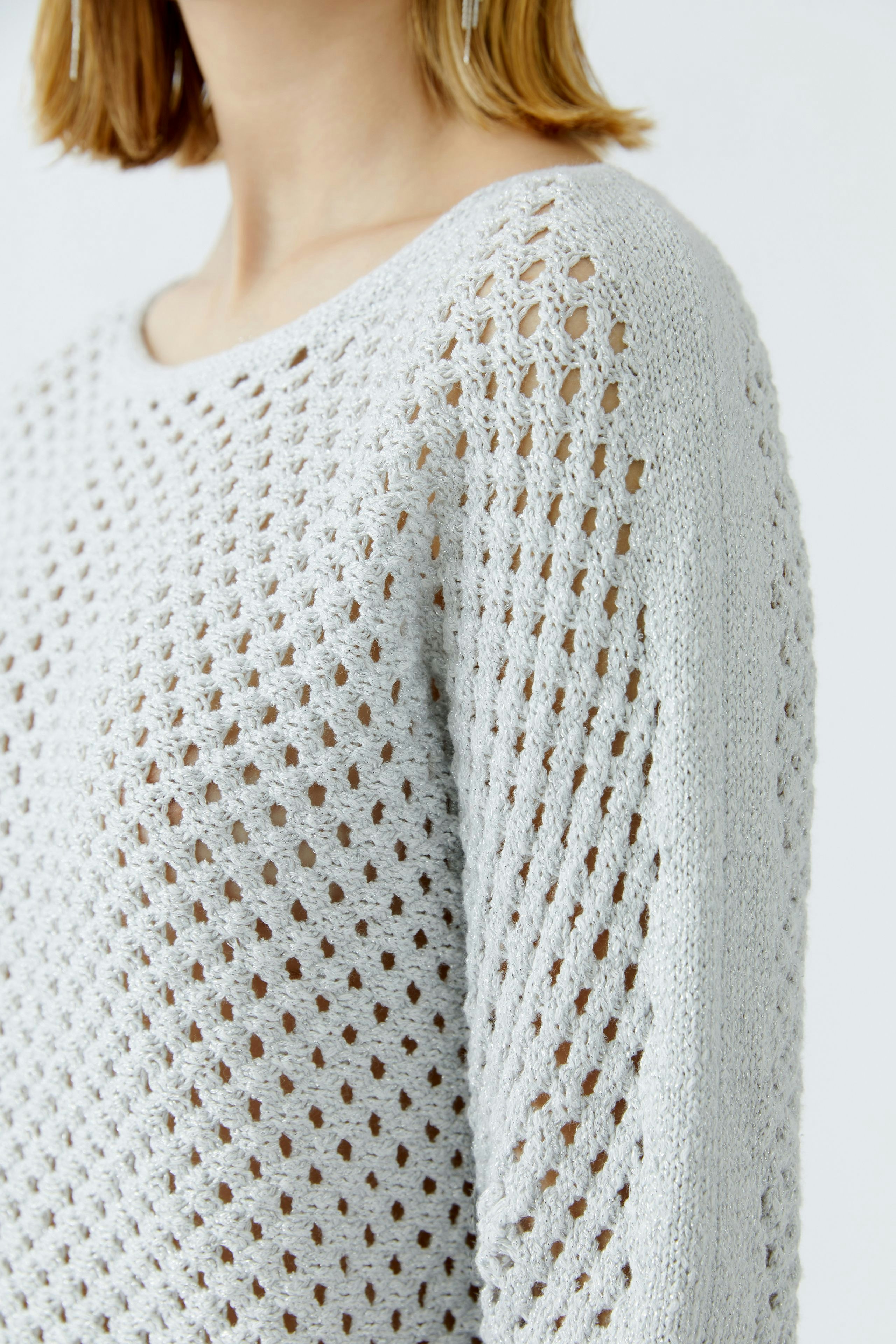 Light grey pullover: Woman in a loose-knit pullover with an open pattern, showcasing a relaxed style.