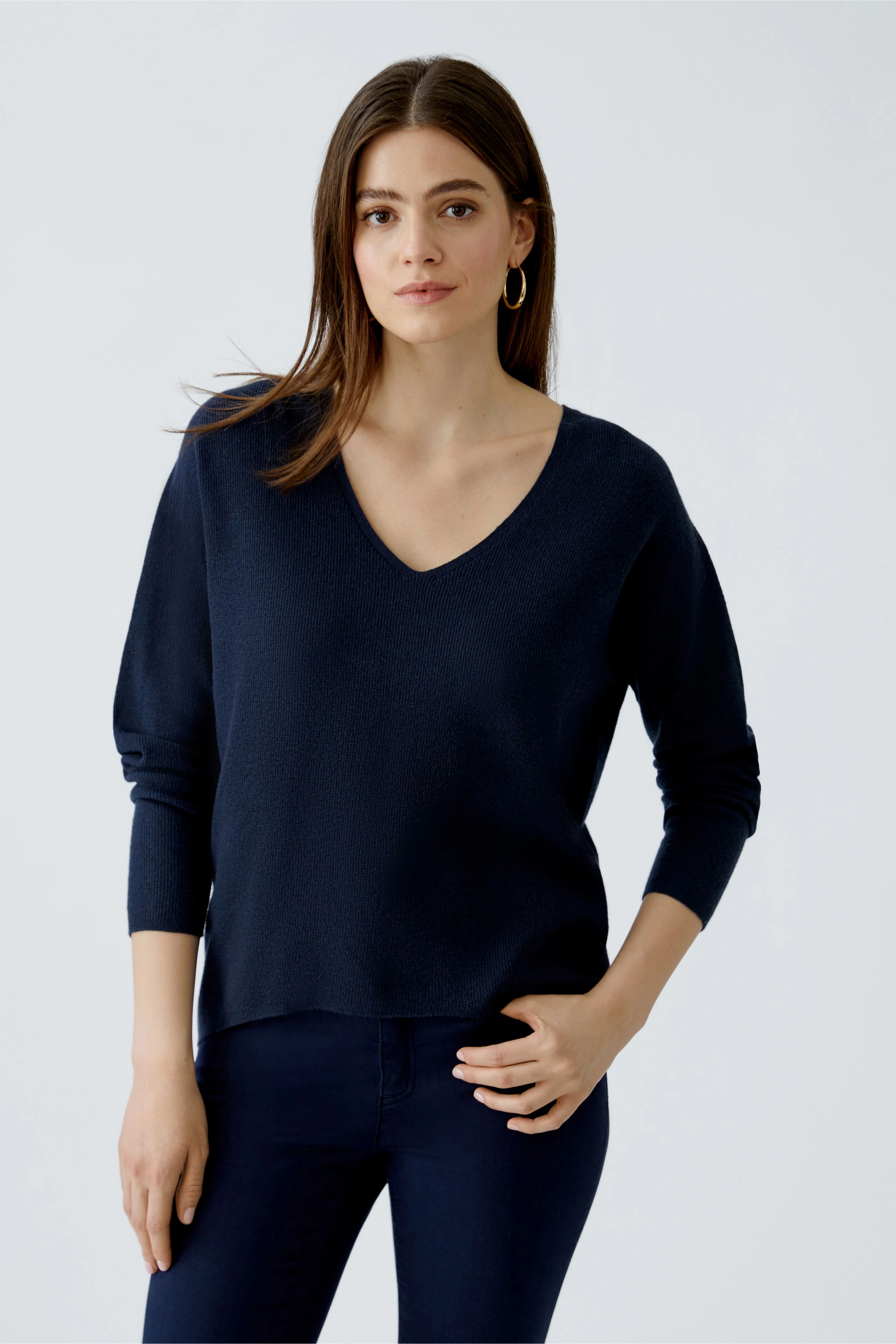 Casual women's pullover: Young woman in a navy V-neck pullover, paired with dark pants, exuding a relaxed vibe.