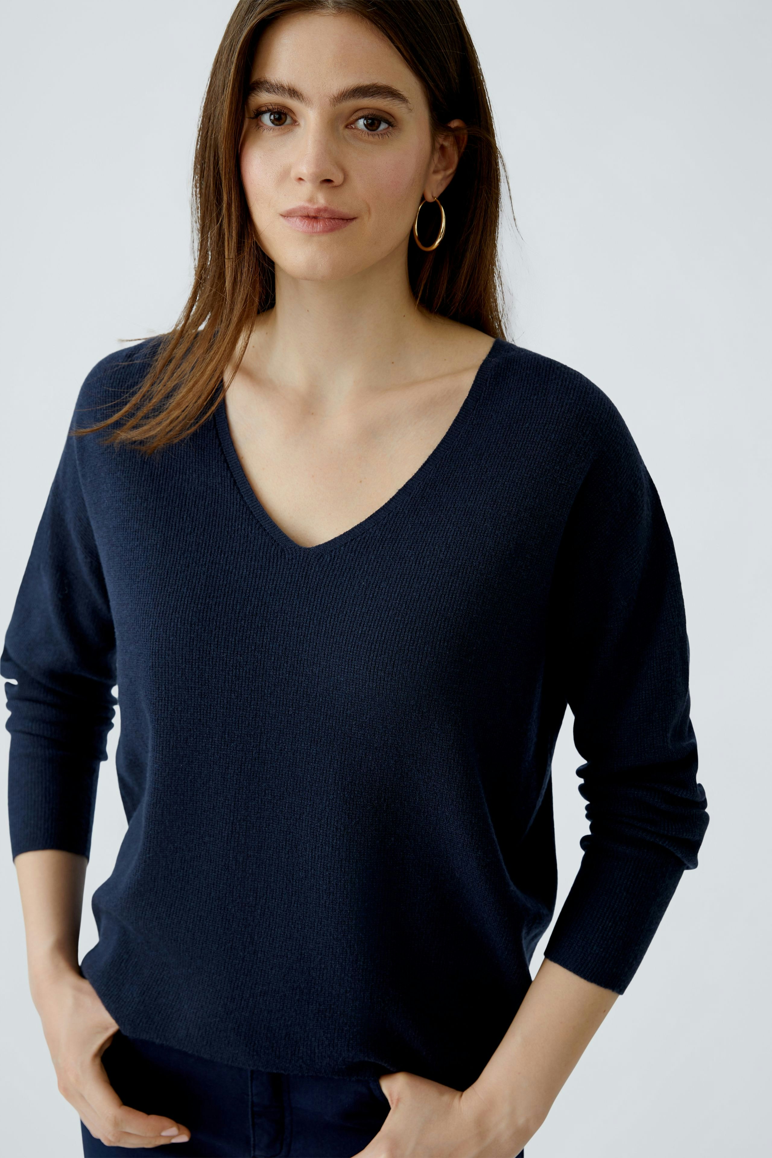 Casual women's pullover: Young woman in a navy V-neck pullover, looking relaxed and confident.