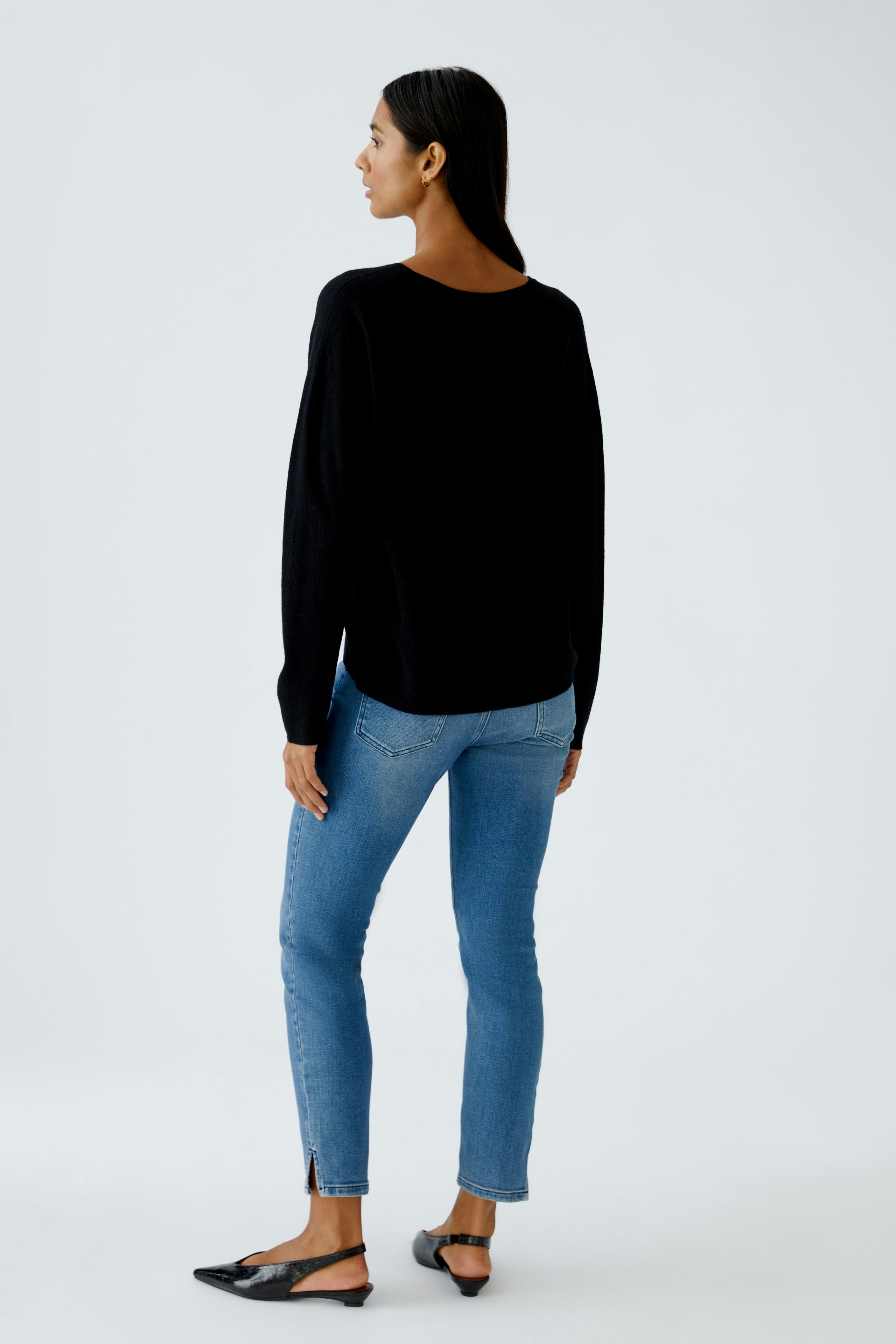 Casual women's pullover: A woman in a black pullover with a relaxed fit, paired with blue jeans.