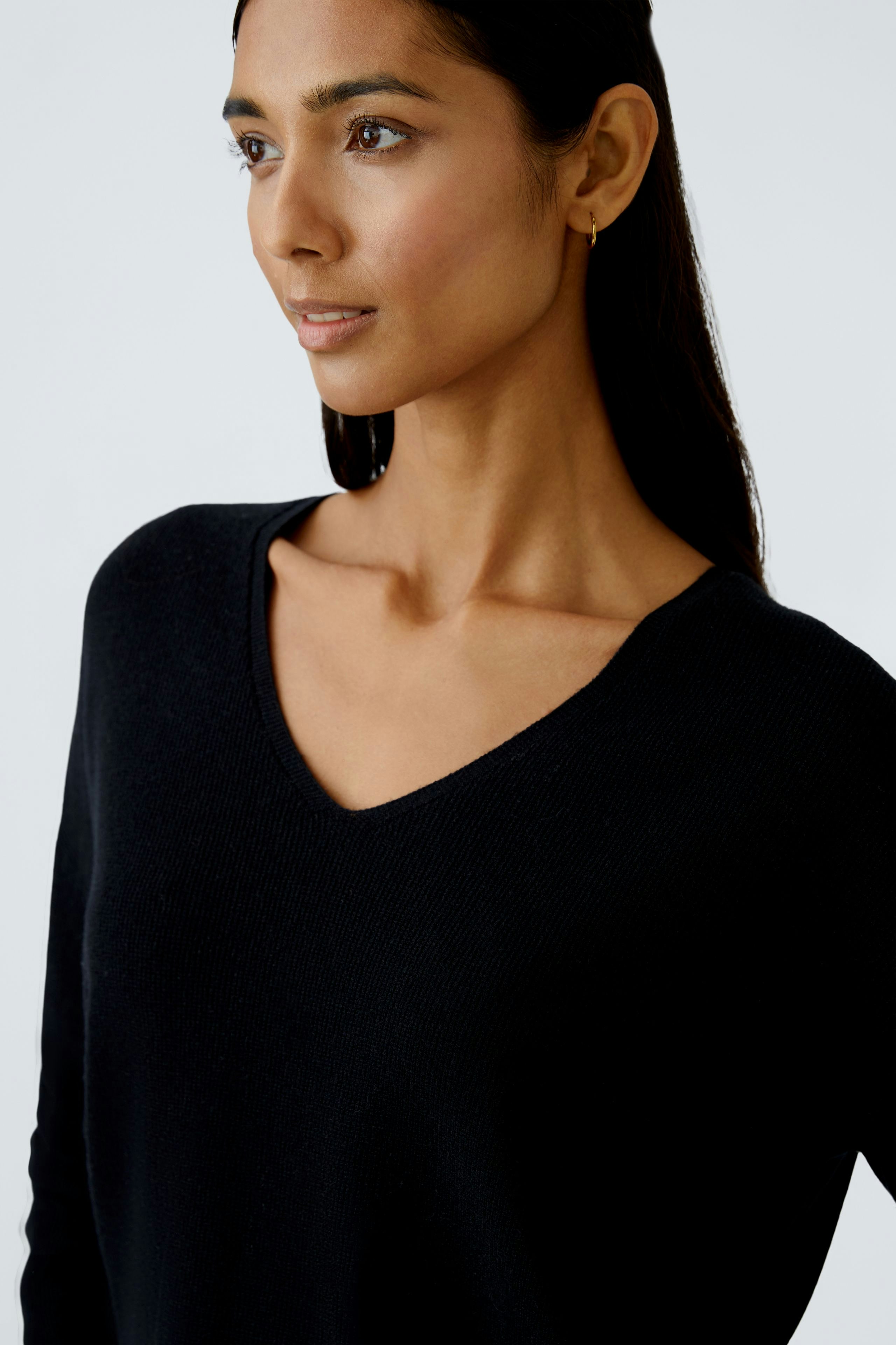 Modern women's pullover: A woman in a black V-neck pullover, showcasing a relaxed style.