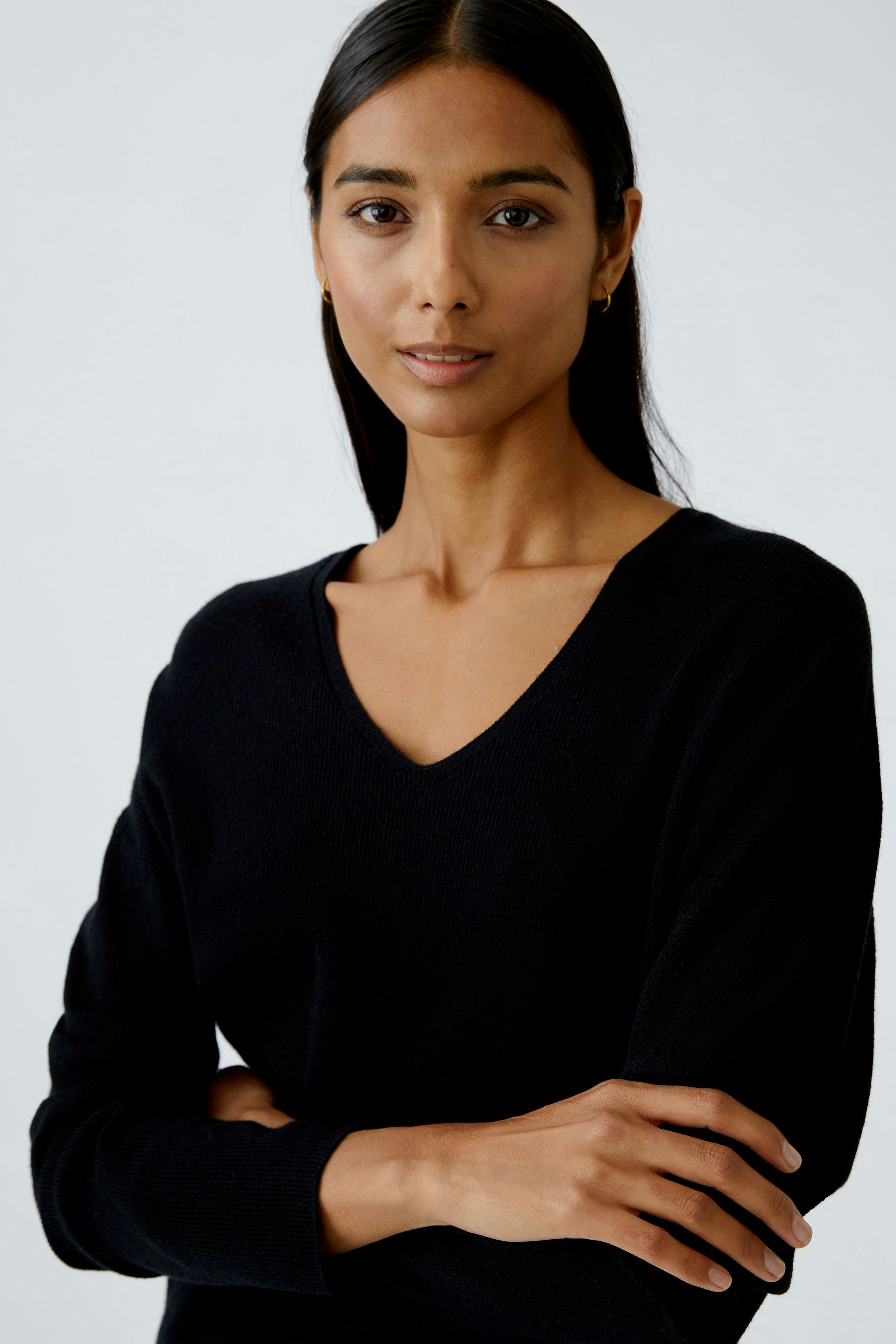 Modern women's pullover: Woman in a black V-neck pullover, showcasing a relaxed and casual style.