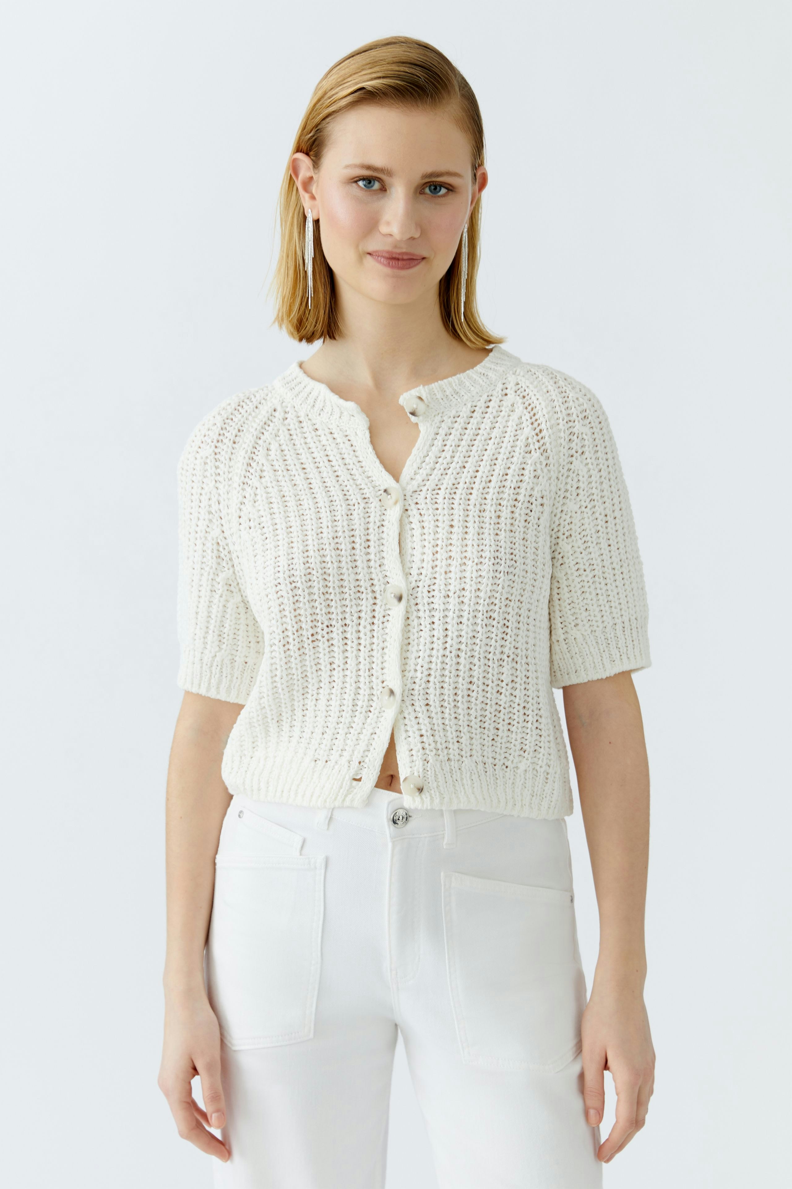 Casual women's cardigan: A woman in a short-sleeved, white knitted cardigan with buttons.