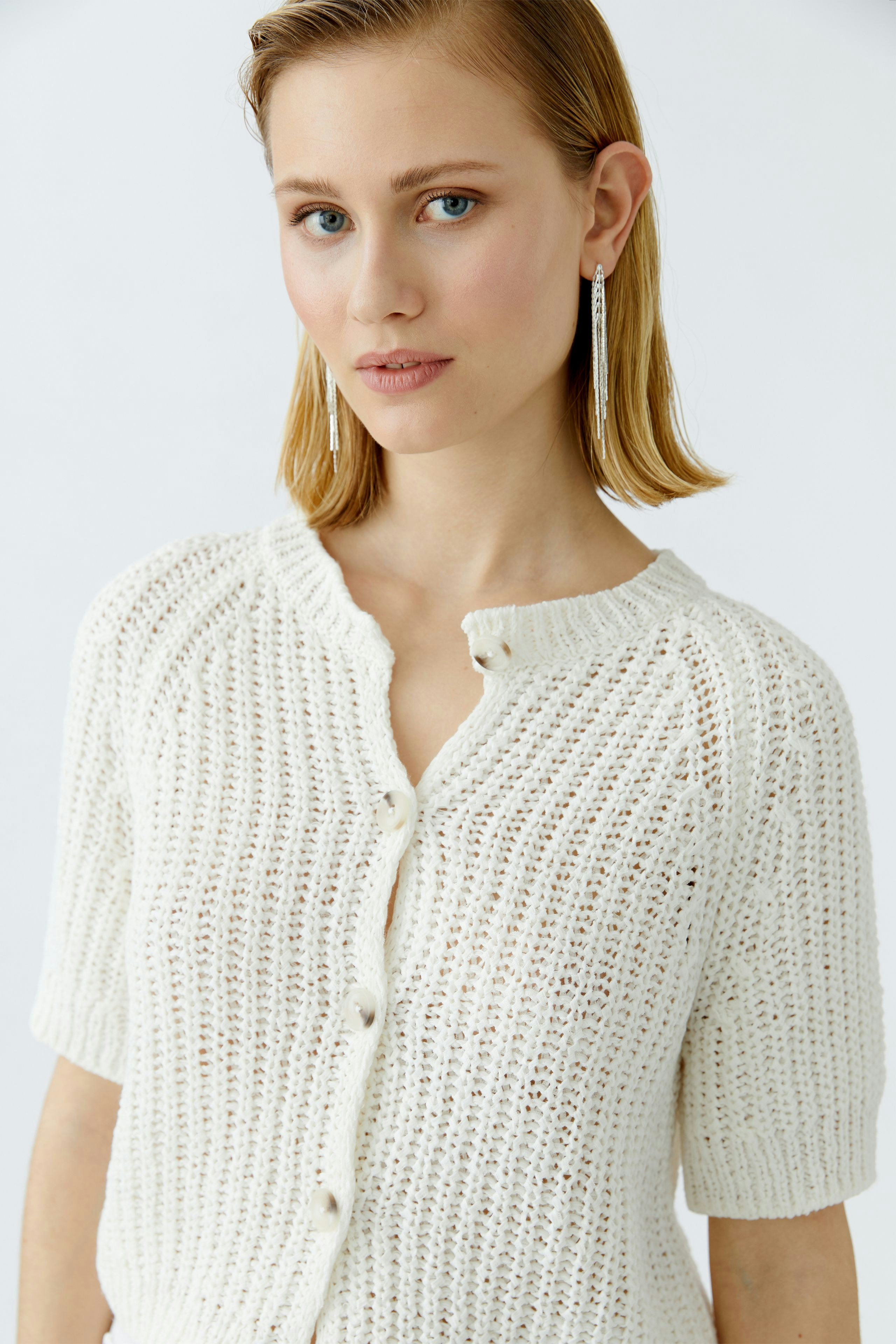 Casual women's cardigan: Young woman in a white knitted cardigan with short sleeves and buttons.