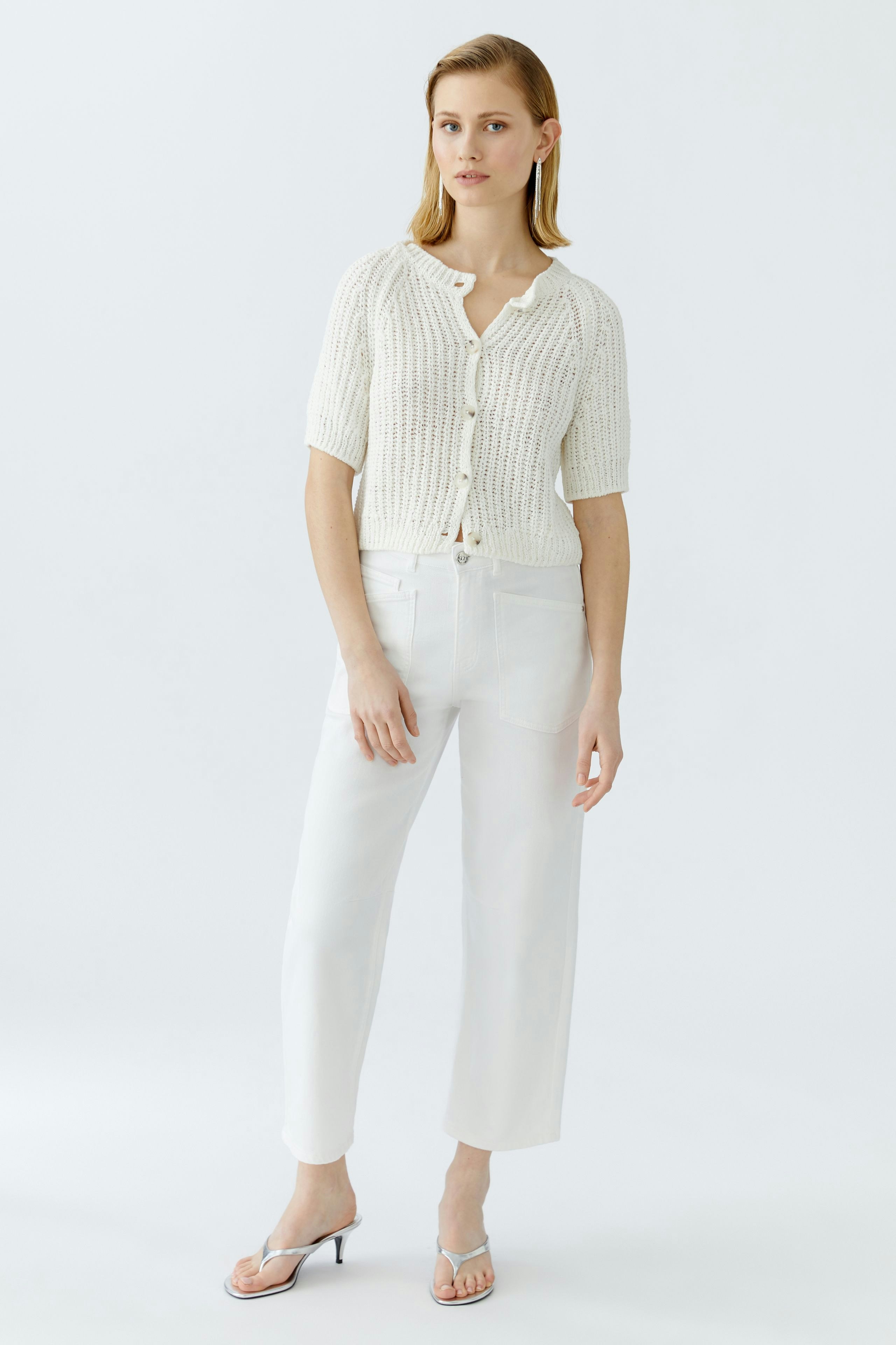 Casual women's cardigan: A woman in a white knitted cardigan with short sleeves and buttons stands confidently.