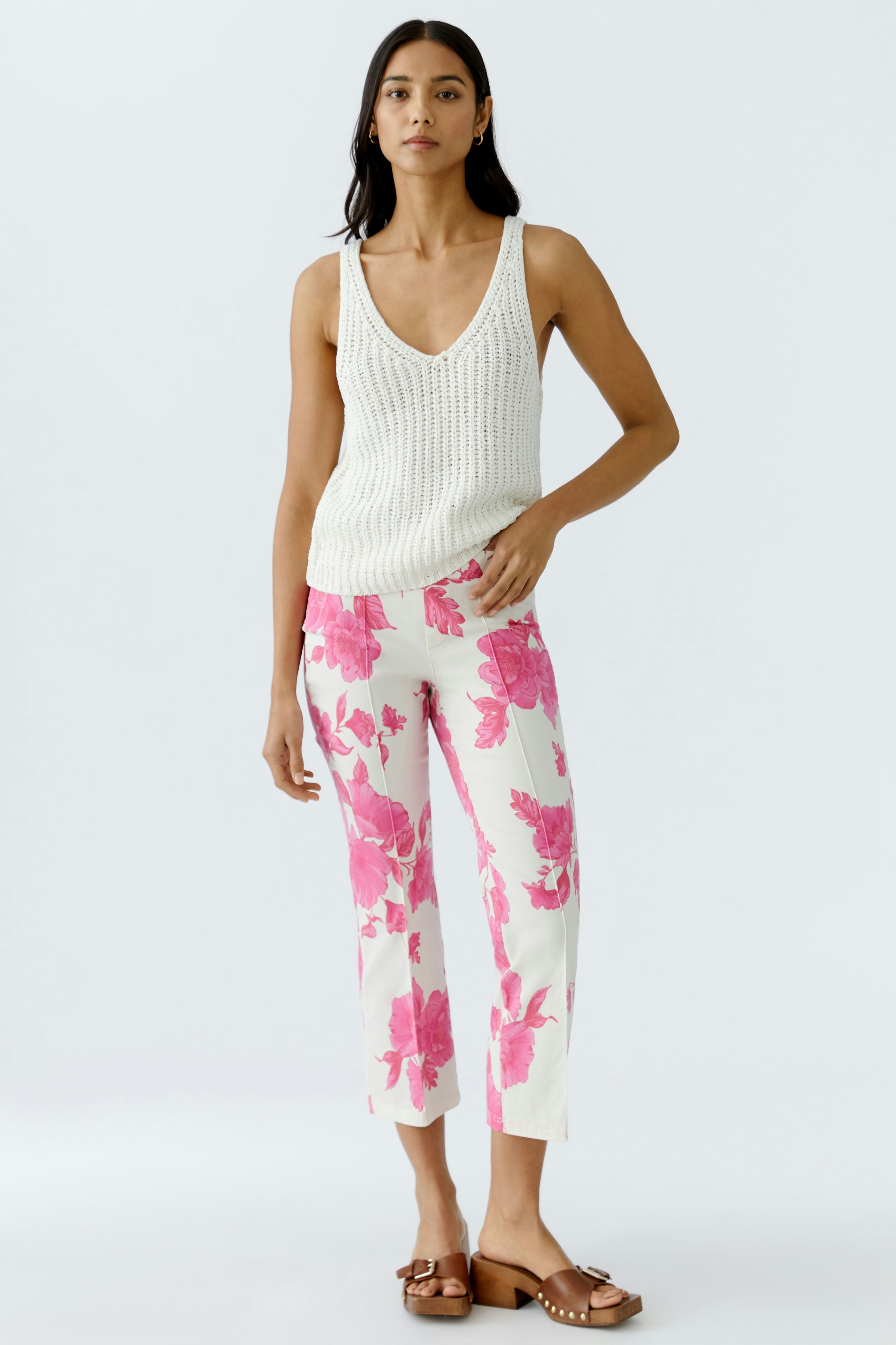 Helle Damen-Hose mit floralem Muster: Frau trägt eine modische Hose in Weiß mit pinken Blumen.