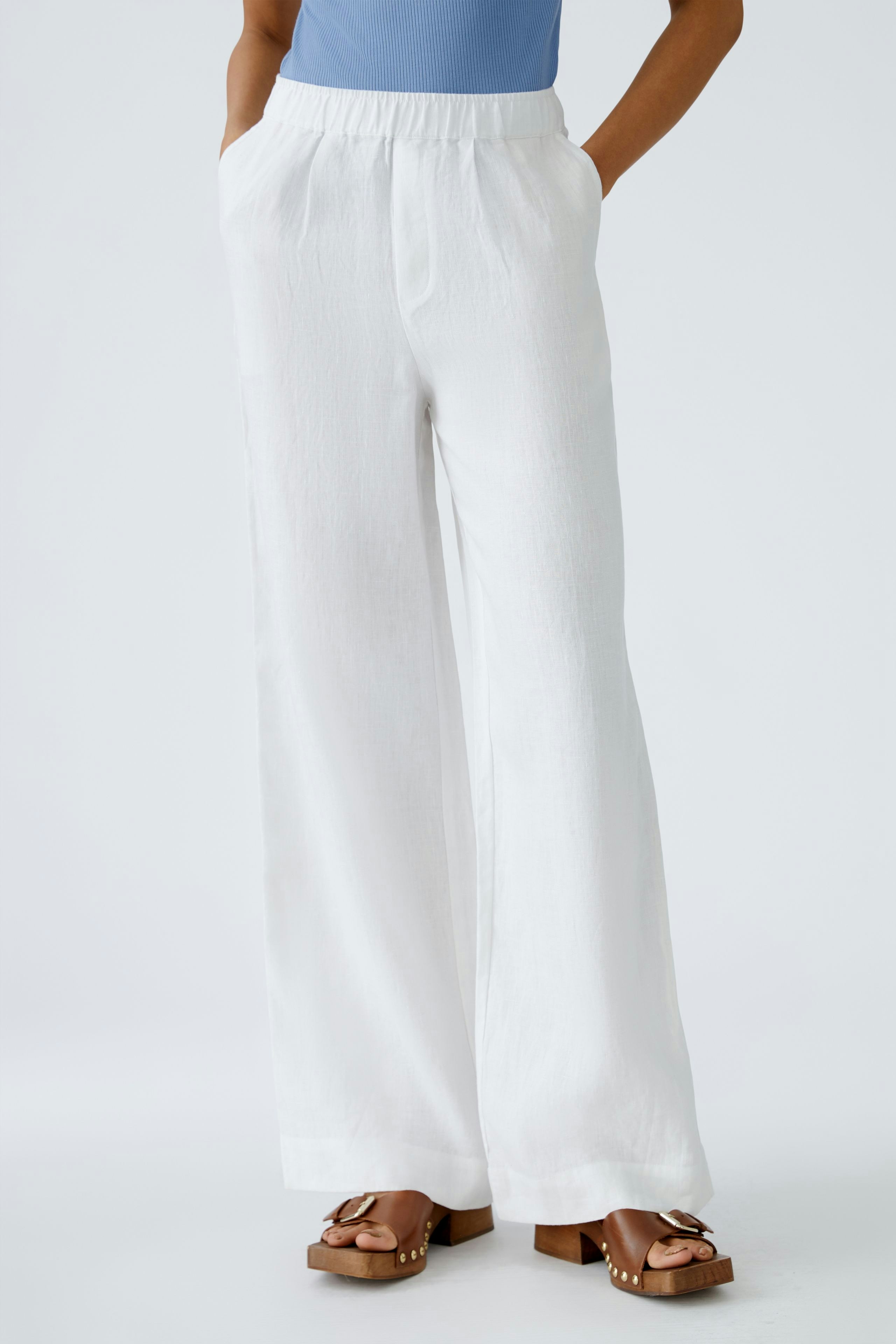 Elegante Damen-Hose: Frau in weißer, weit geschnittener Hose mit elastischem Bund und lässigen Sandalen.