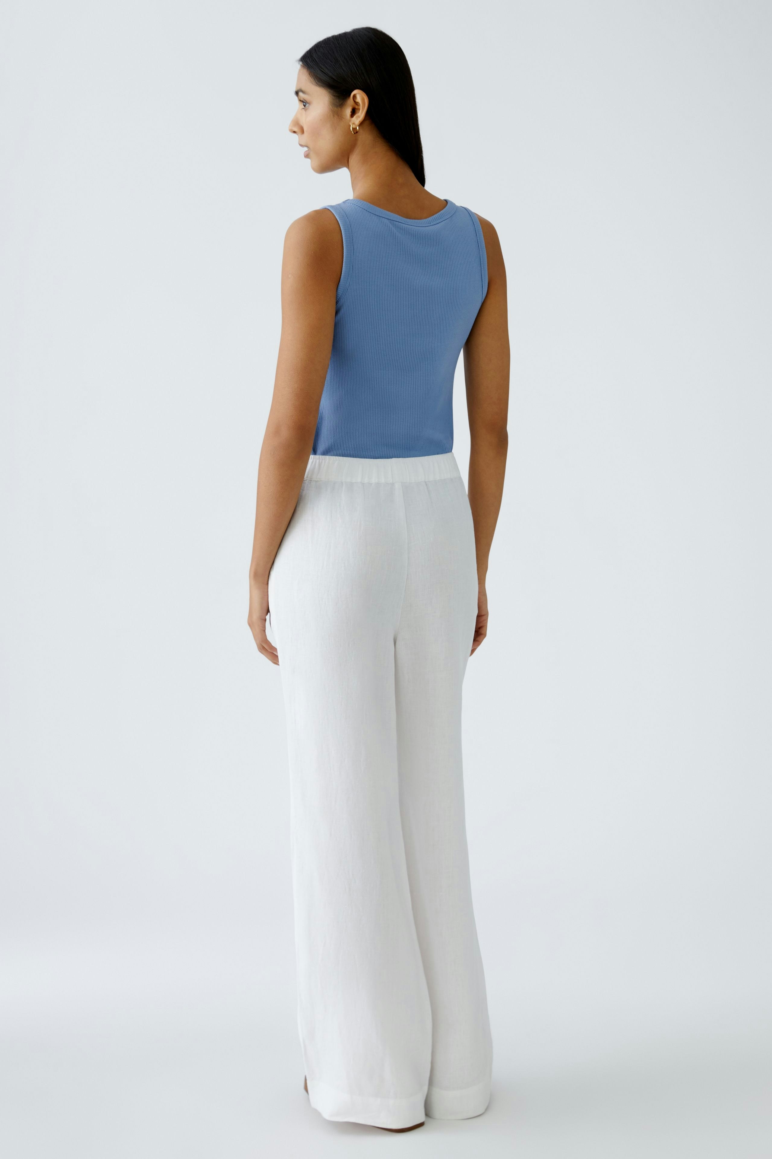 Elegante Damen-Hose: Frau in weißer, weiter Hose mit elastischem Bund und lässigem Oberteil.