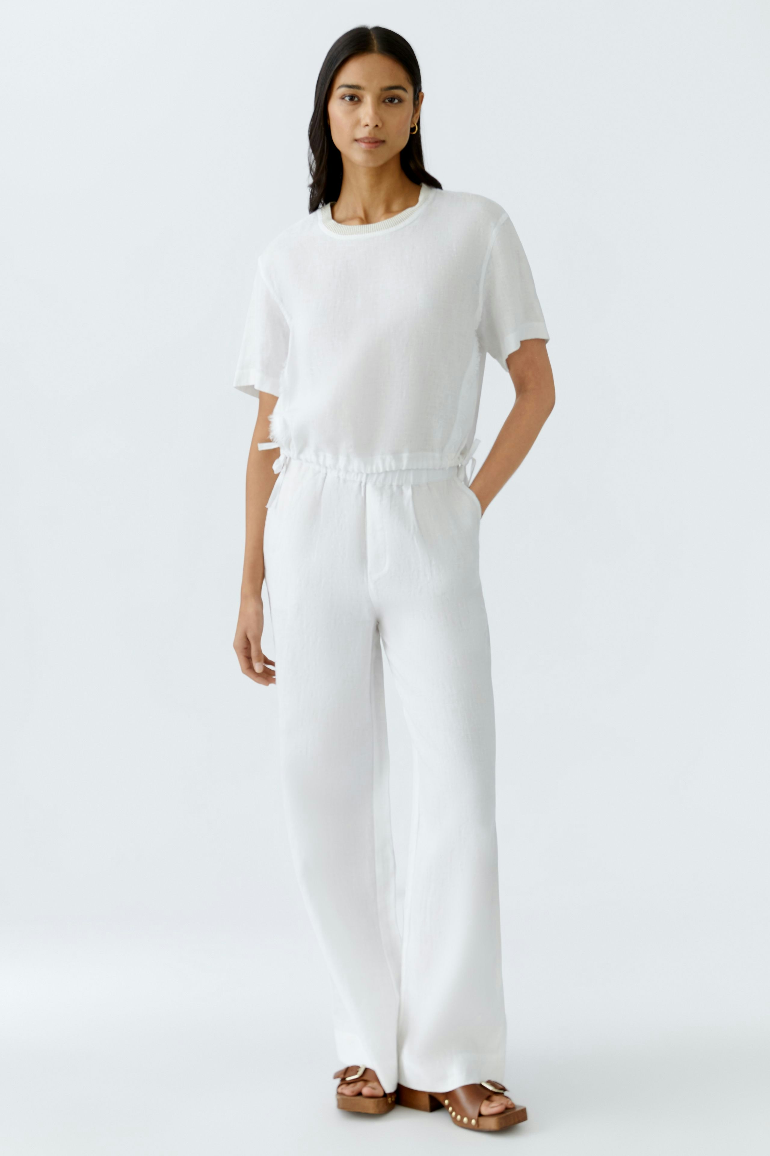 Luftige Damen-Hose: Frau in weißer Hose mit elastischem Bund und lässigem T-Shirt.