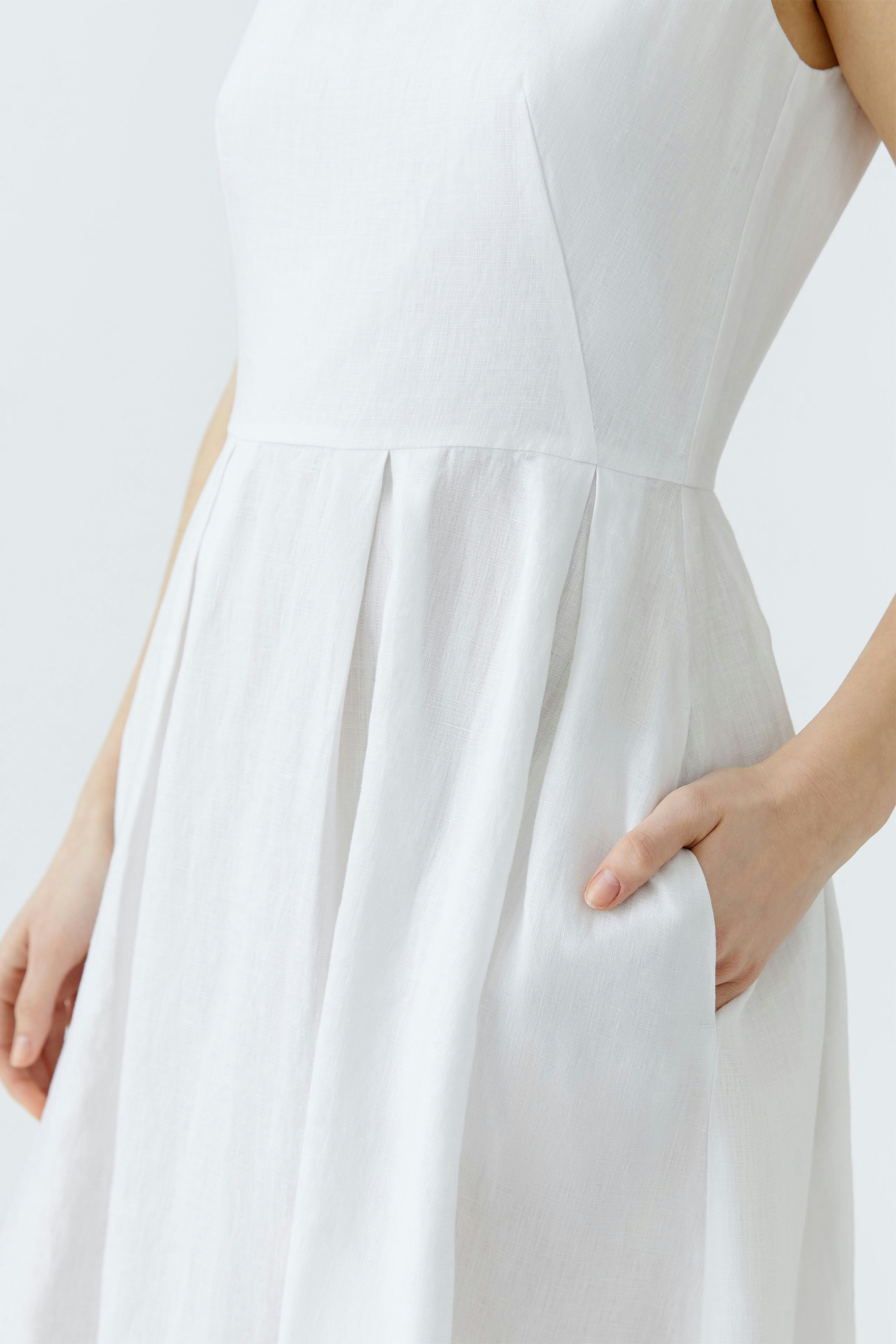 Casual midi dress: Woman in a white dress with a fitted bodice and flowing skirt, featuring side pockets.