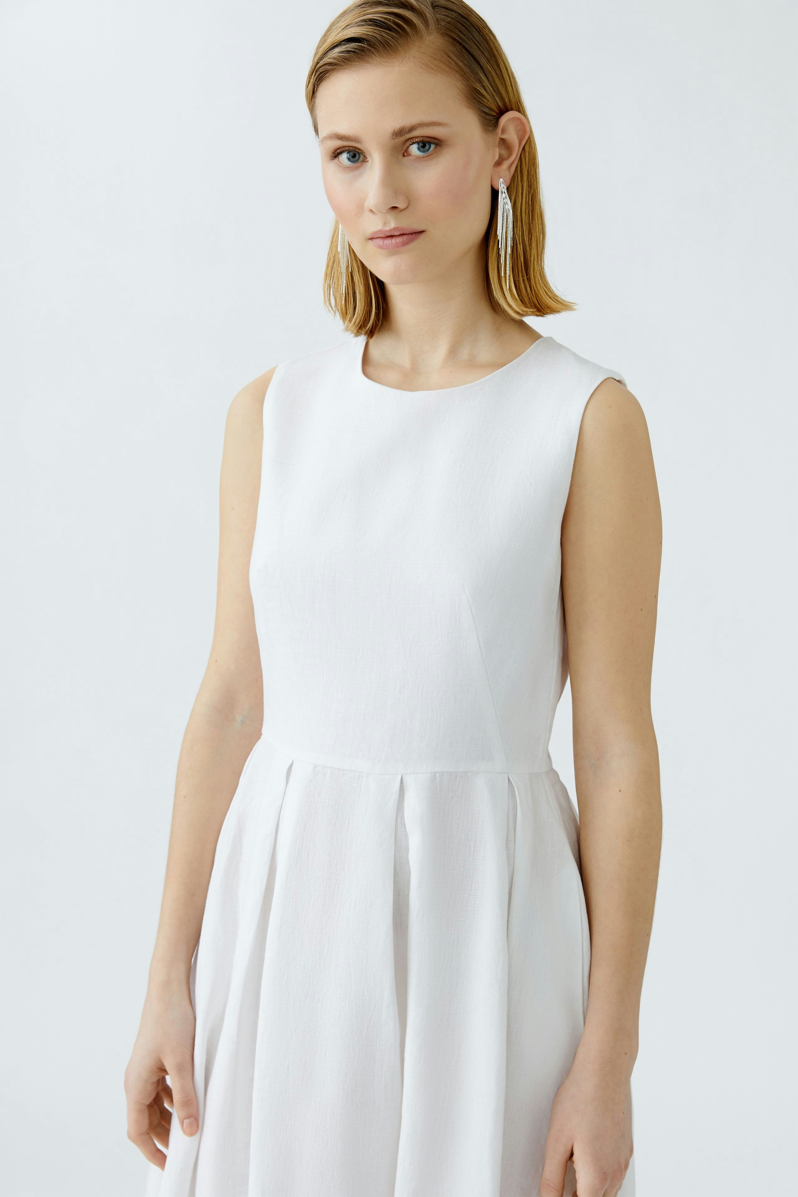 Casual midi dress: A woman in a white sleeveless midi dress with a simple design, looking confidently.