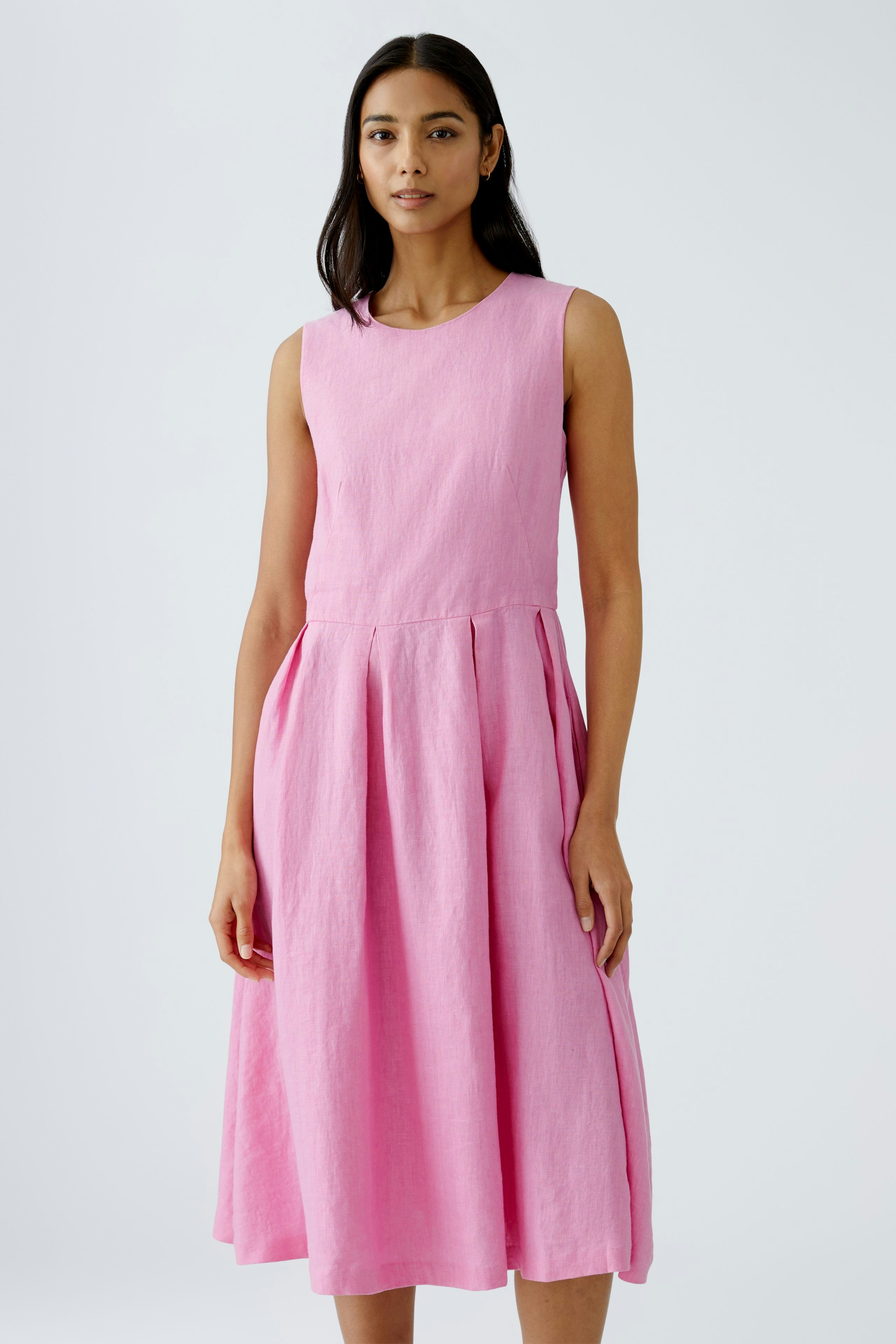 Elegantes Midikleid in Pink: Frau trägt ein ärmelloses Kleid mit fließendem Rock.