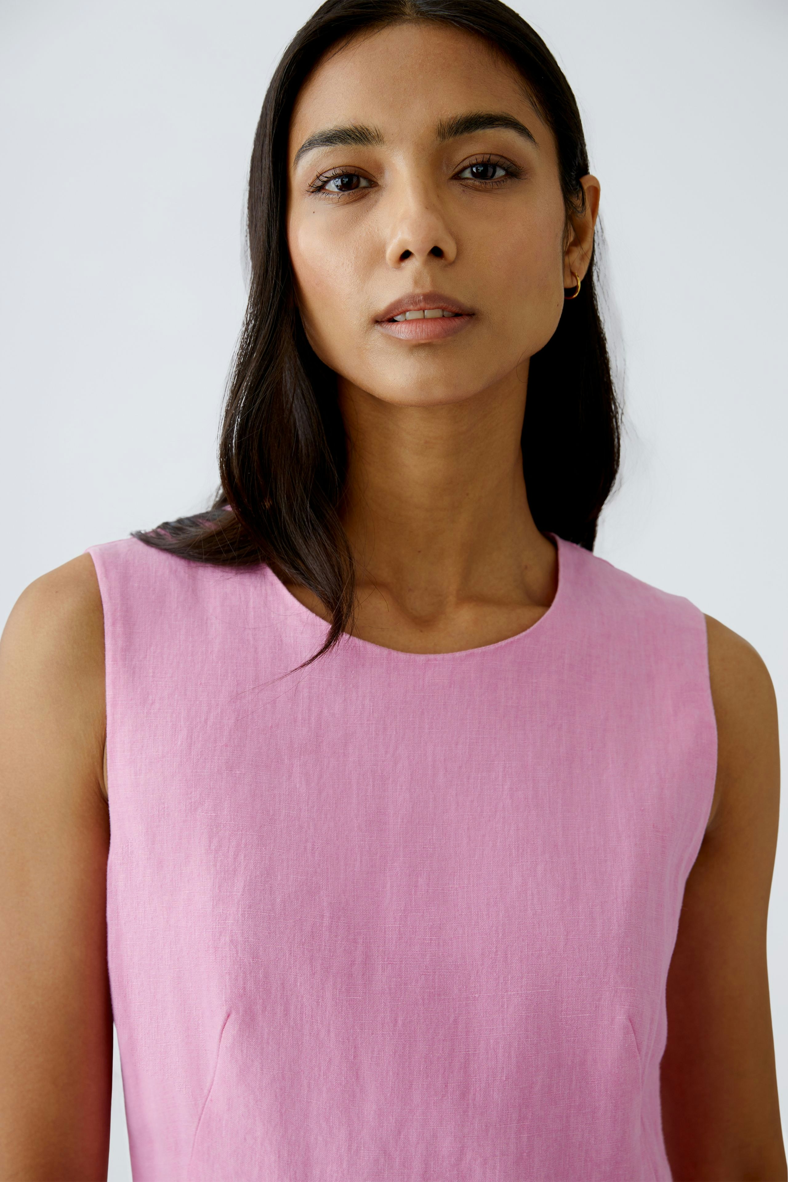 Elegantes Midikleid: Frau in einem rosa Kleid mit schlichtem Design und Rundhalsausschnitt.