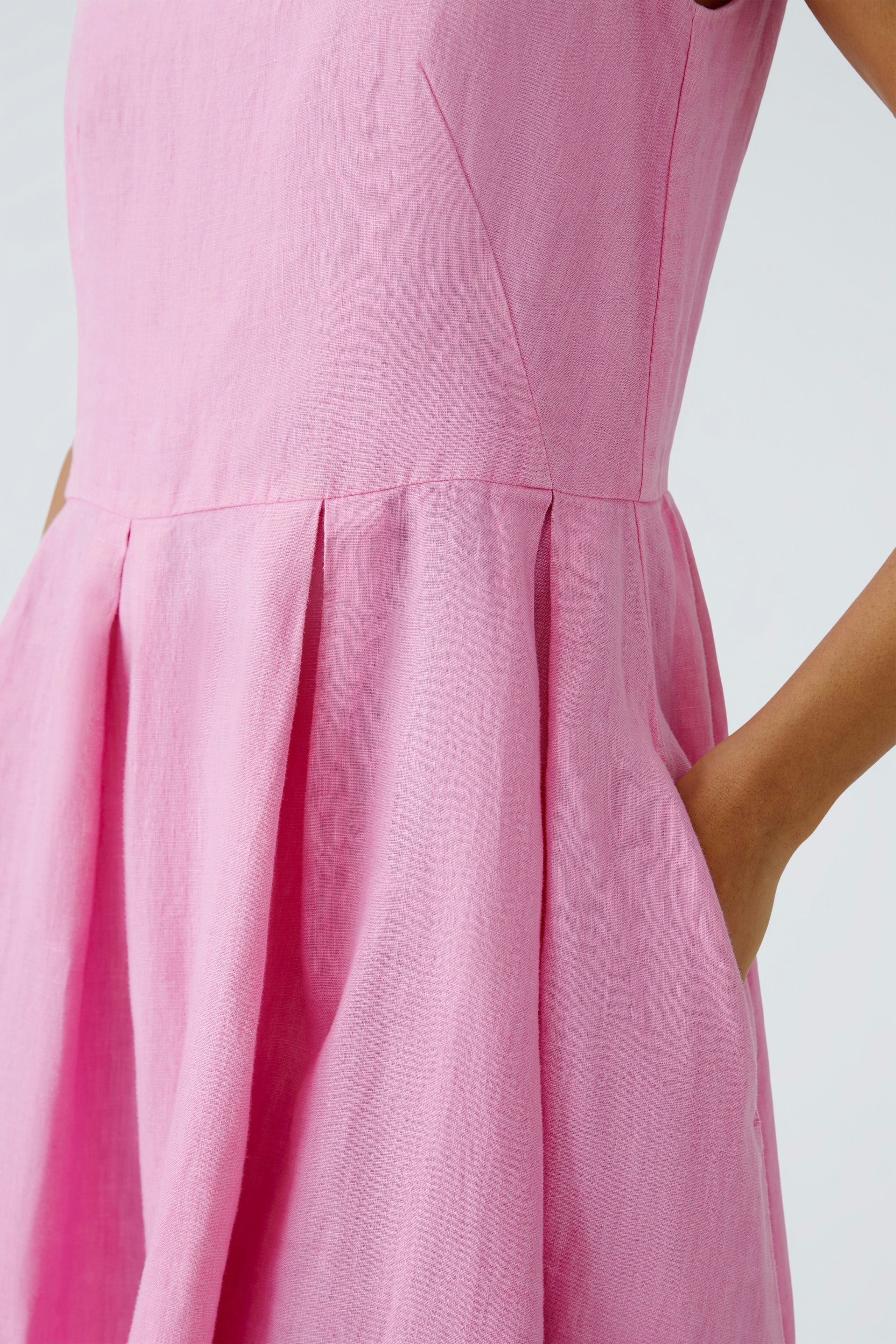 Elegantes Midikleid in Pink: Frau mit schlichter Silhouette und praktischen Taschen.