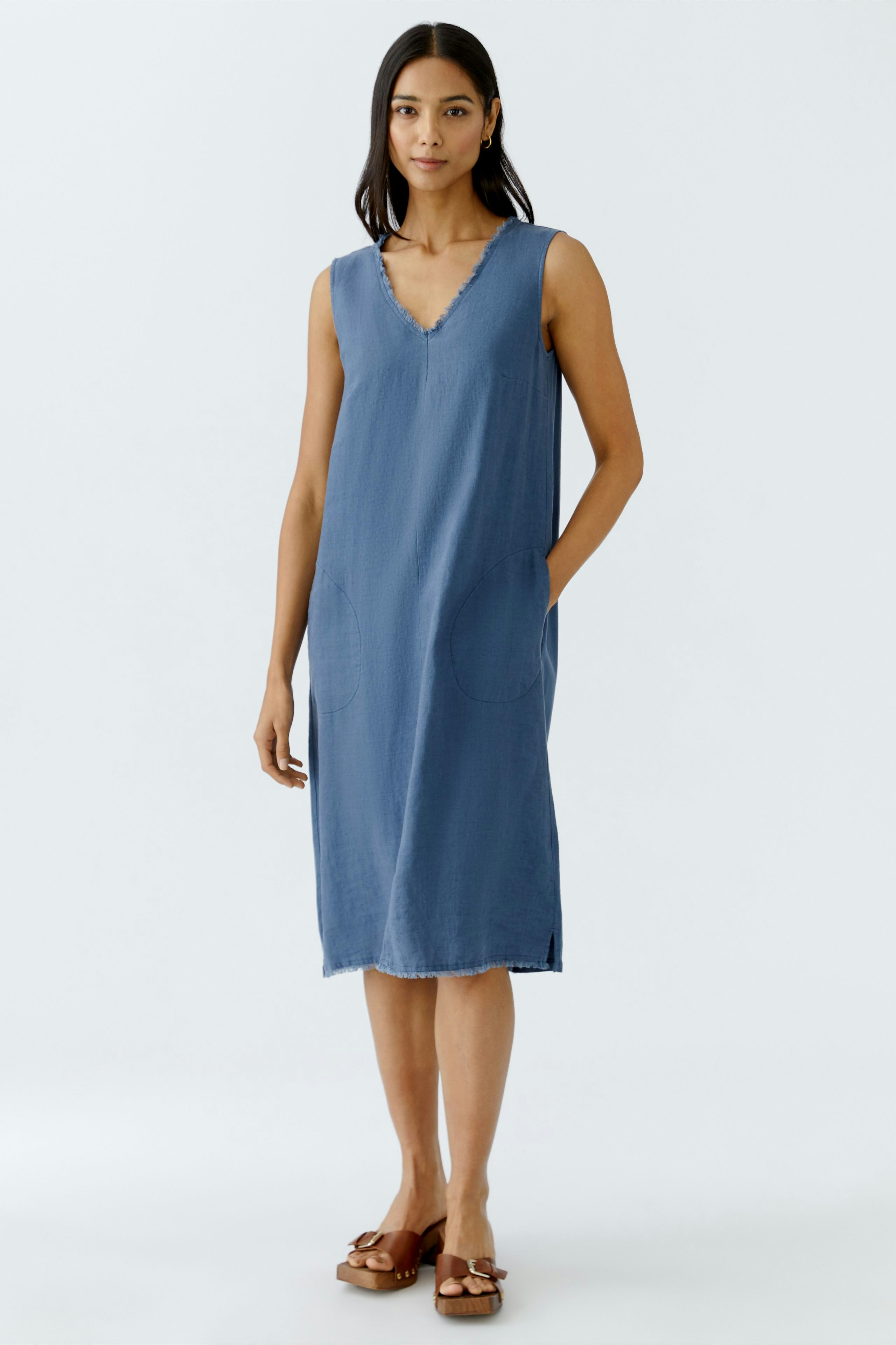 Casual A-line dress: A woman in a sleeveless blue dress with pockets, perfect for warm days.
