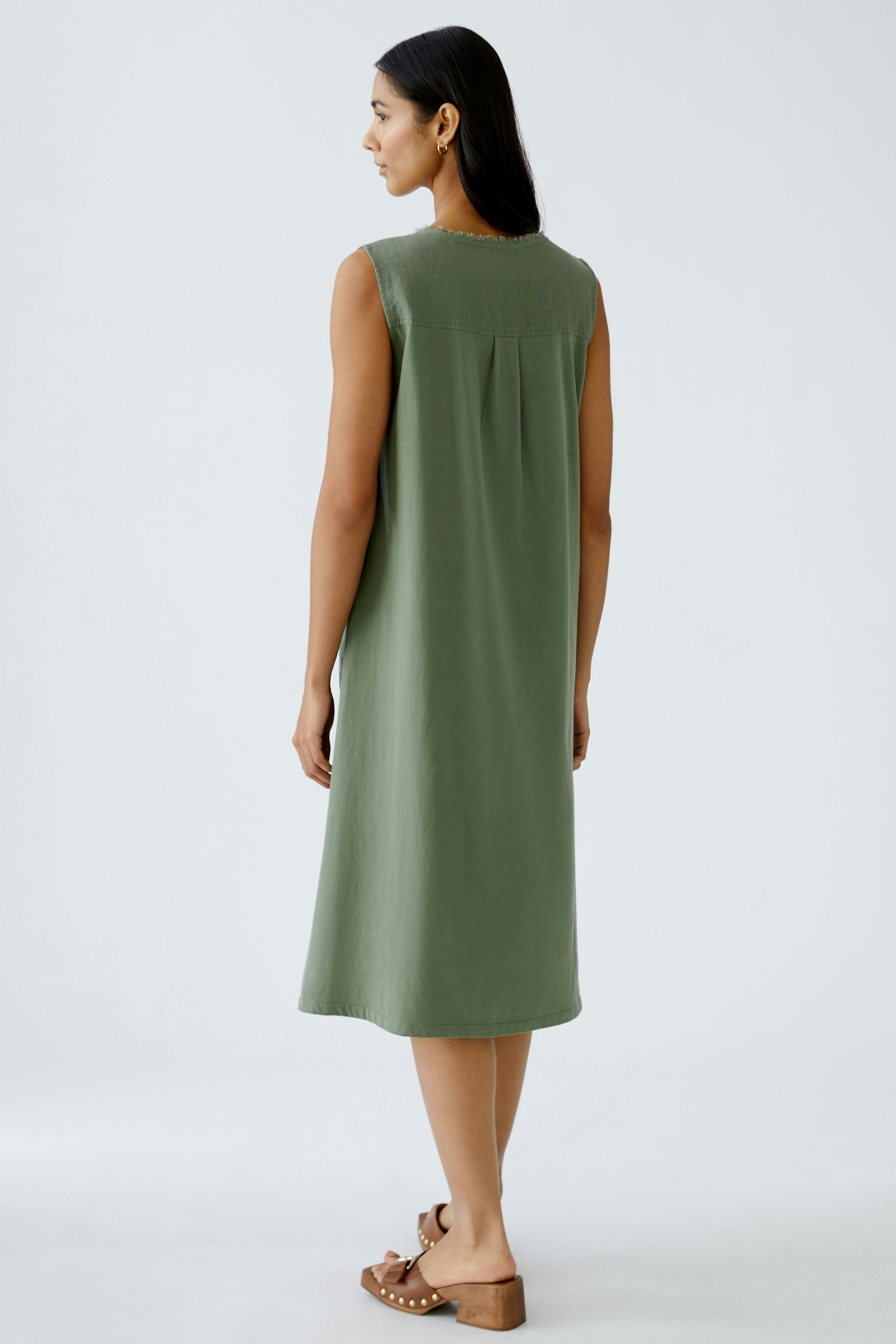 Elegant A-line dress: Woman in a sleeveless green dress, showcasing a relaxed and stylish silhouette.