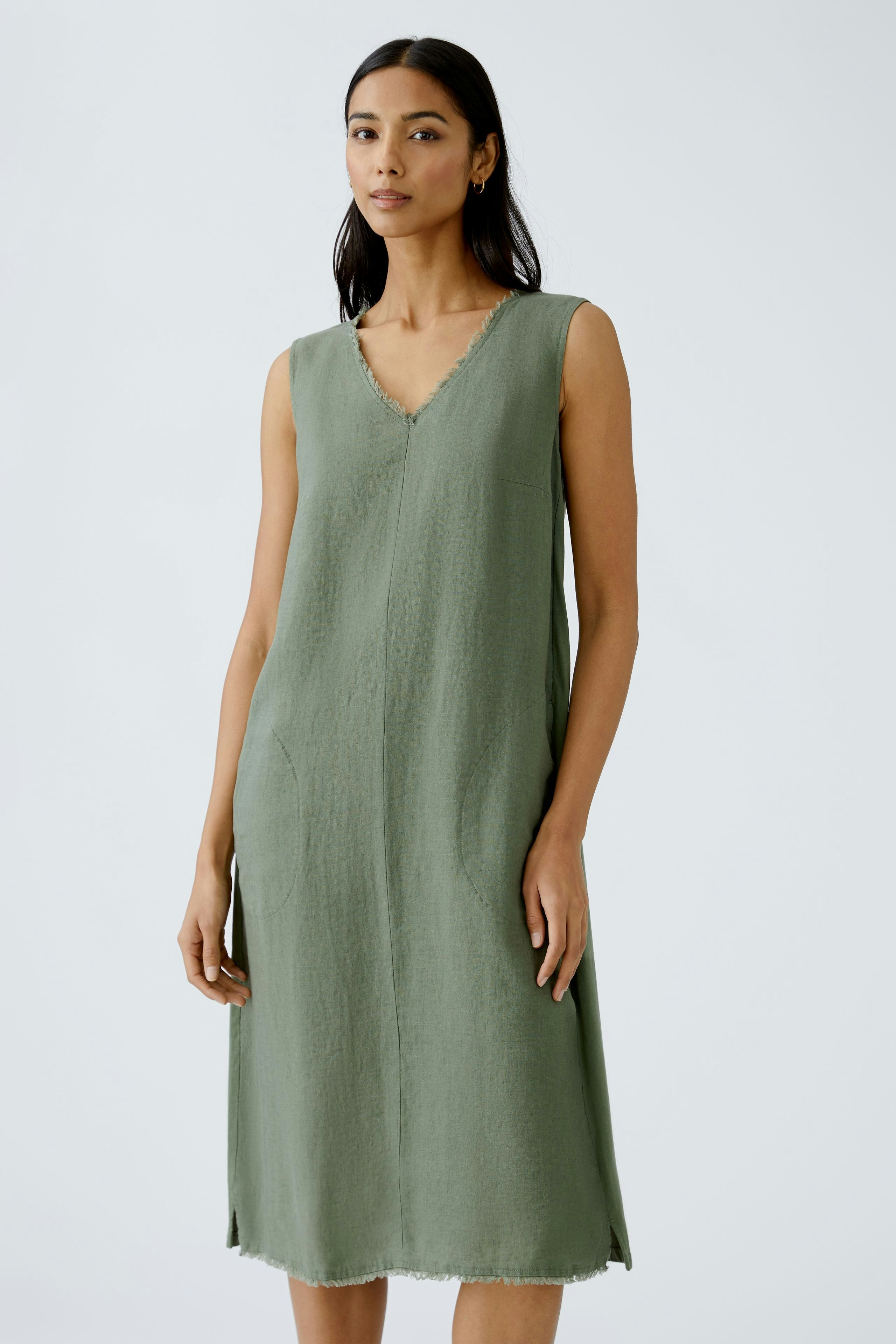 Elegant A-line dress: A woman in a sleeveless green dress with a relaxed fit and pockets.