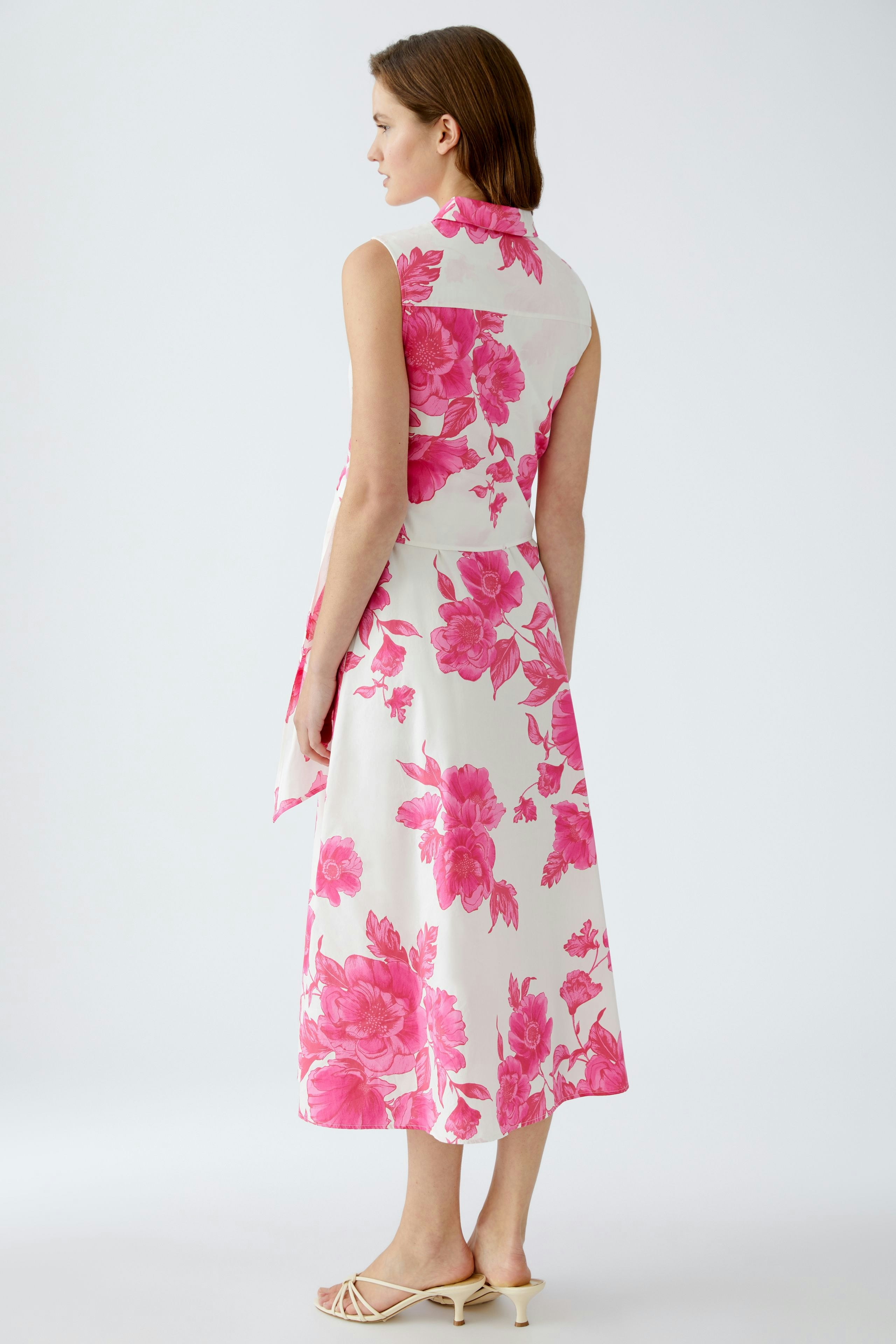 Elegant maxi dress: Woman in a floral print dress with a sleeveless design, showcasing a vibrant pink pattern.