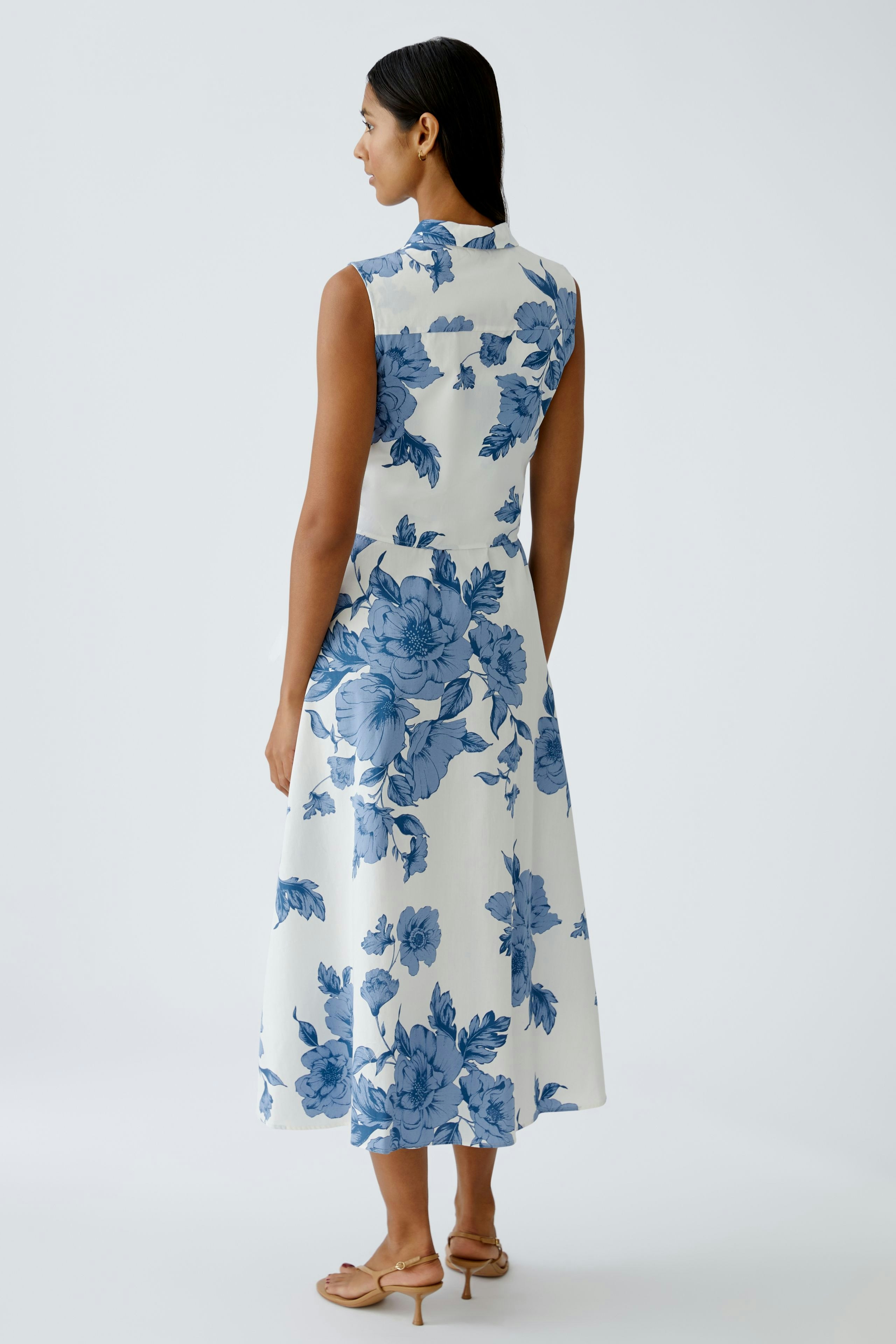 Floral maxi dress: Woman in a sleeveless dress with blue floral patterns, showcasing a relaxed fit.