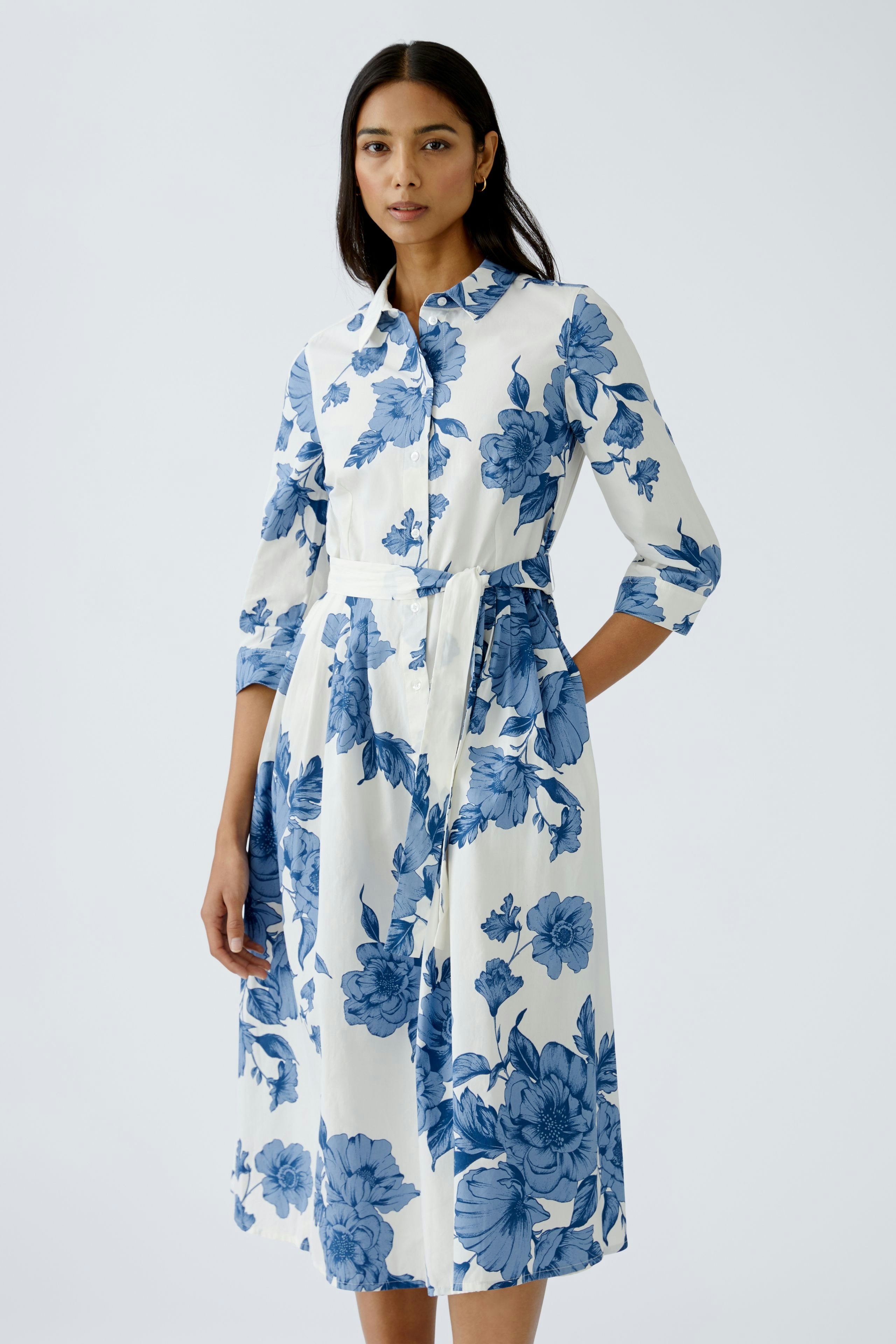 Elegant midi dress: A woman in a floral-patterned dress with a belted waist and button-up front.