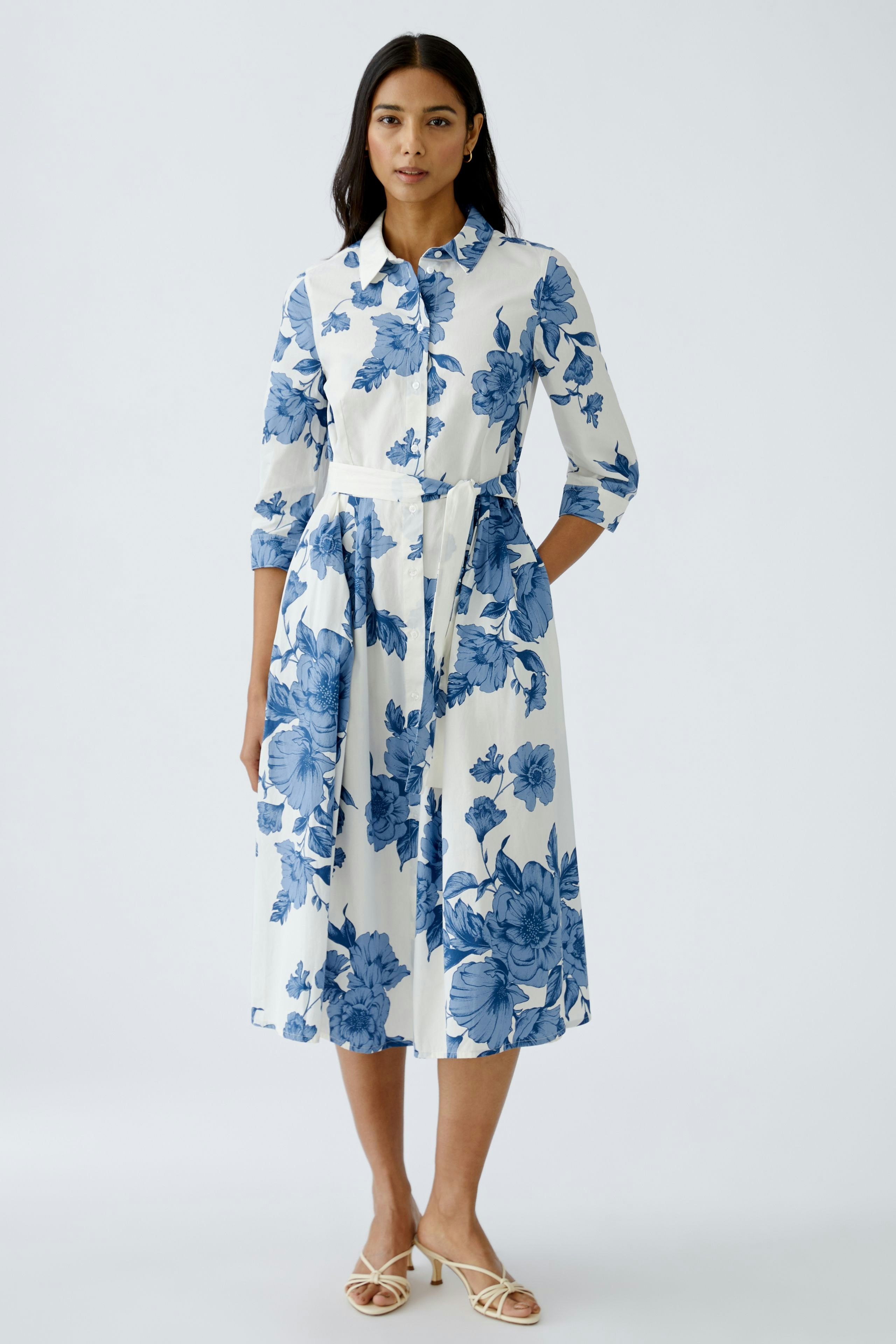 Elegant midi dress: A woman in a floral print dress with a belted waist and button-up design.