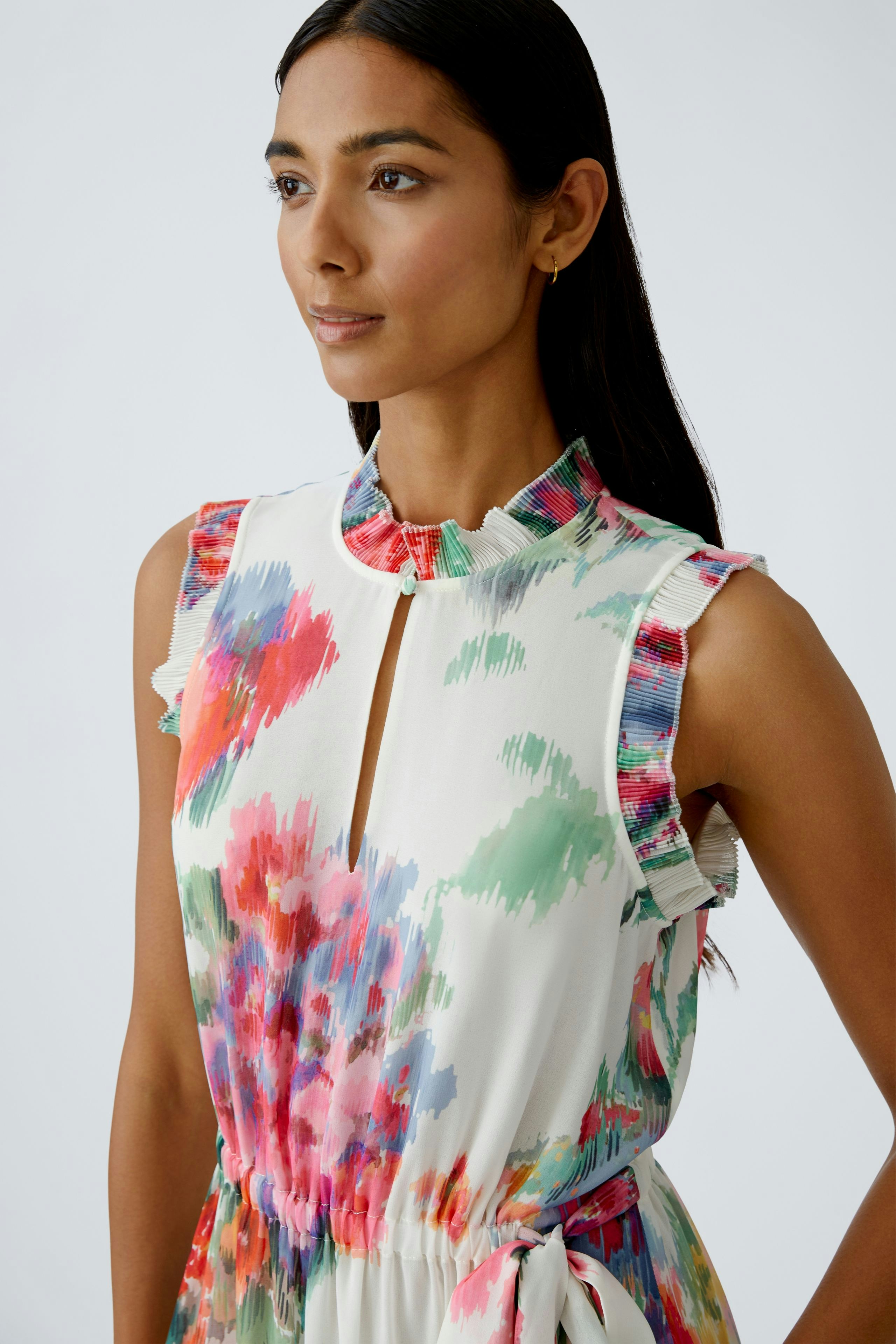 Elegantes Maxikleid: Frau mit buntem, floralem Design und Rüschenkragen, ideal für besondere Anlässe.