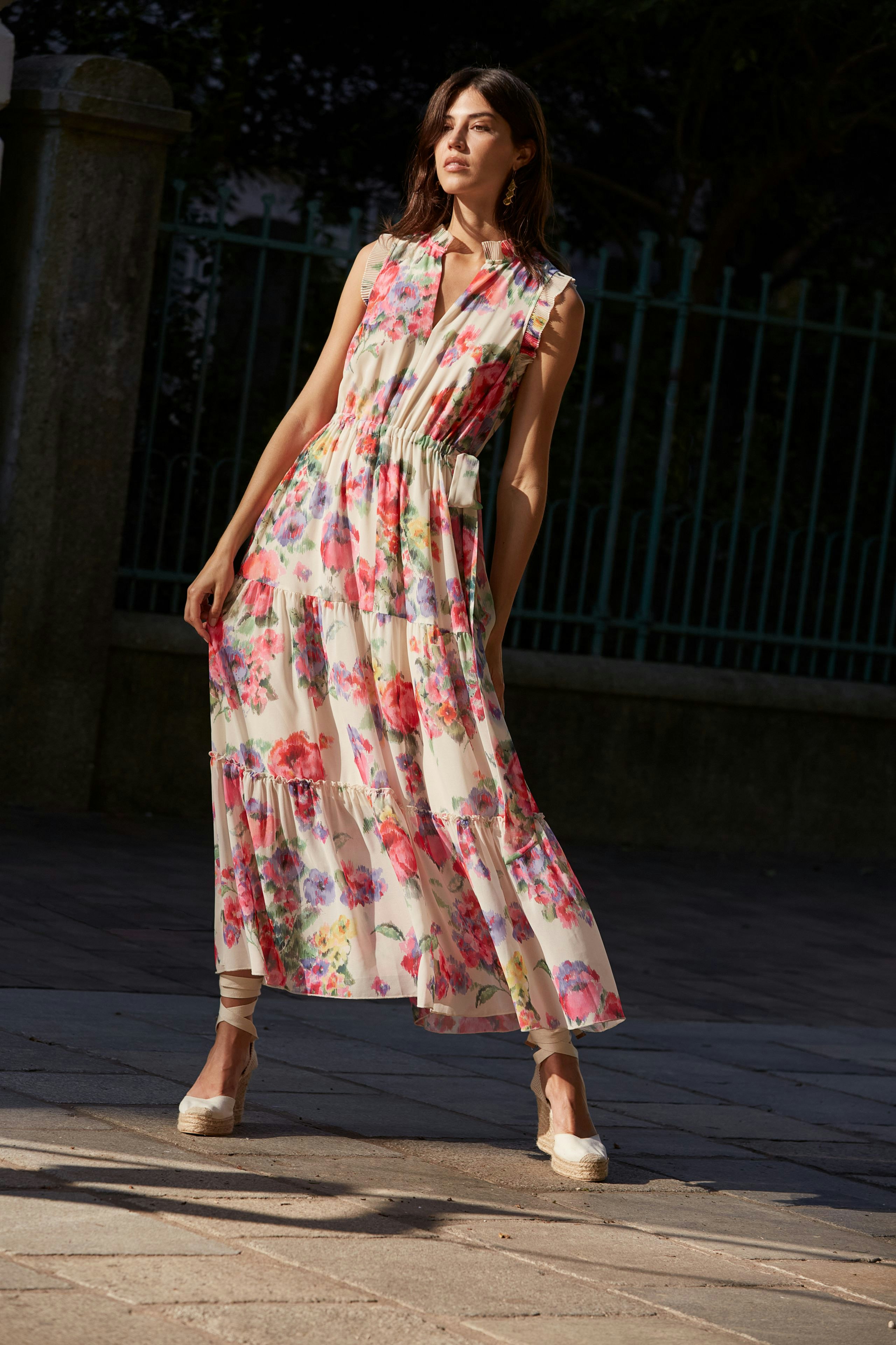 Maxikleid: Frau in floralem, langem Kleid mit fließendem Schnitt und eleganten Sandalen.