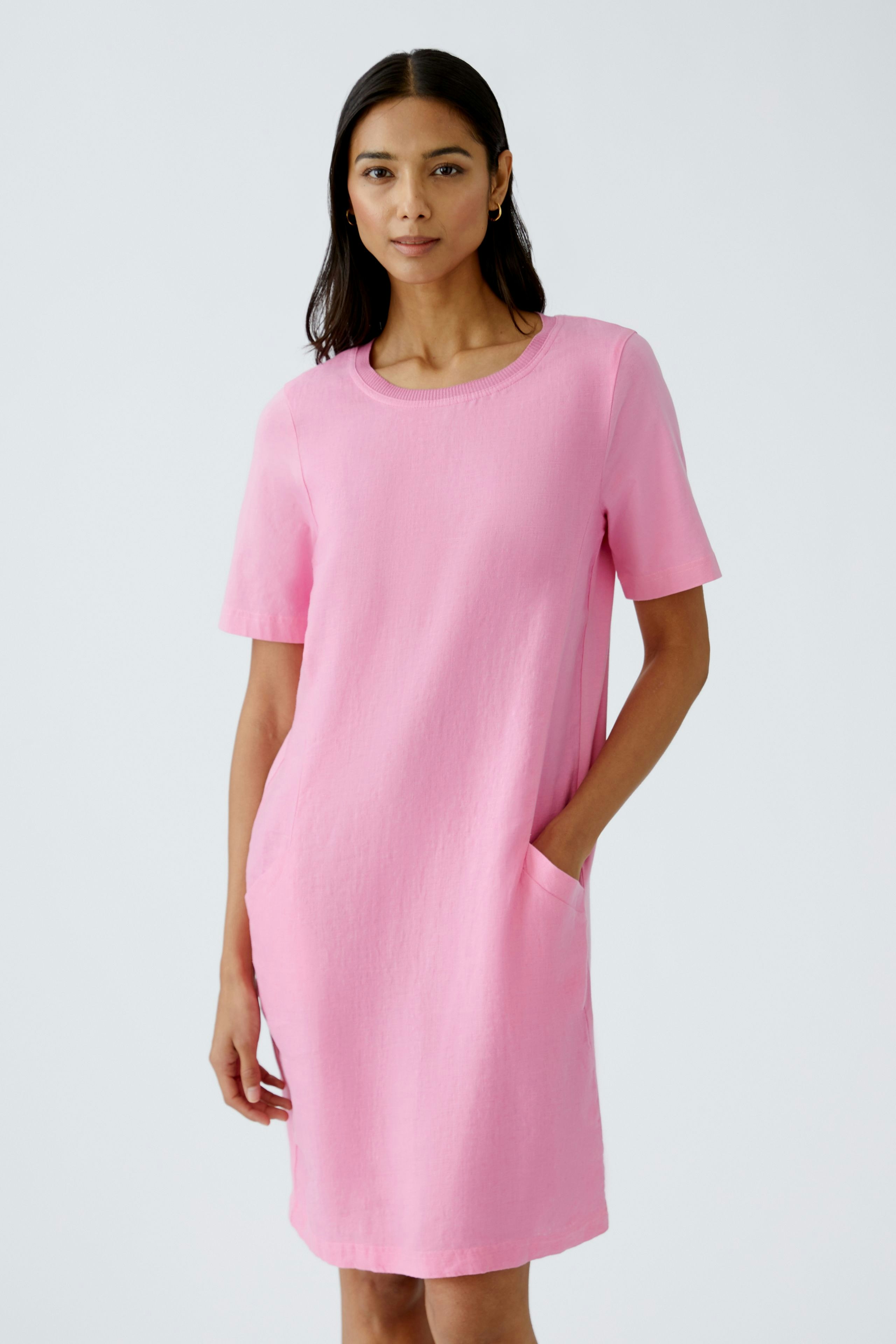 Casual pink dress: Woman in a short-sleeved dress with pockets, exuding effortless style.