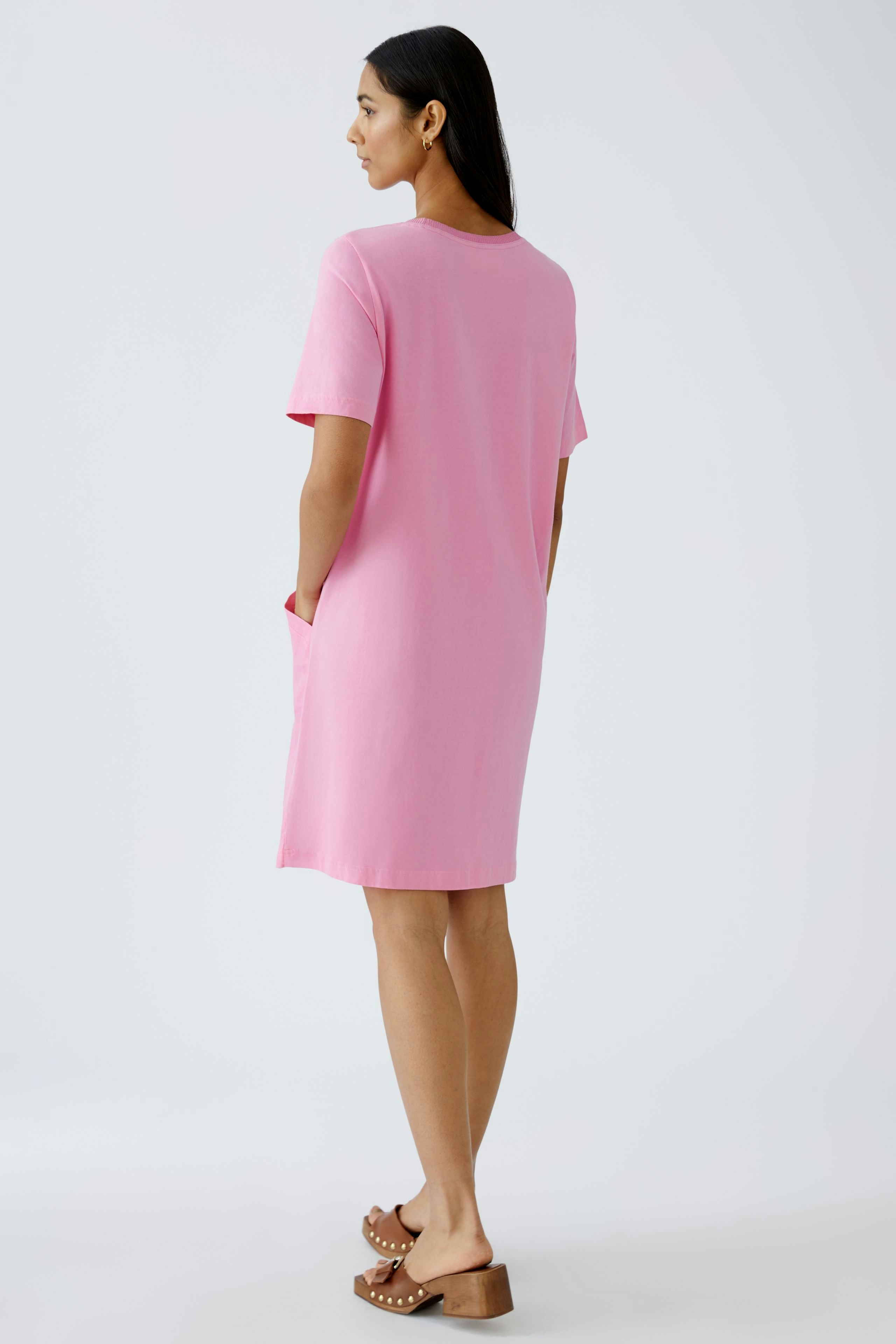 Casual women's dress: A woman in a pink short-sleeve dress with pockets, showcasing a relaxed style.