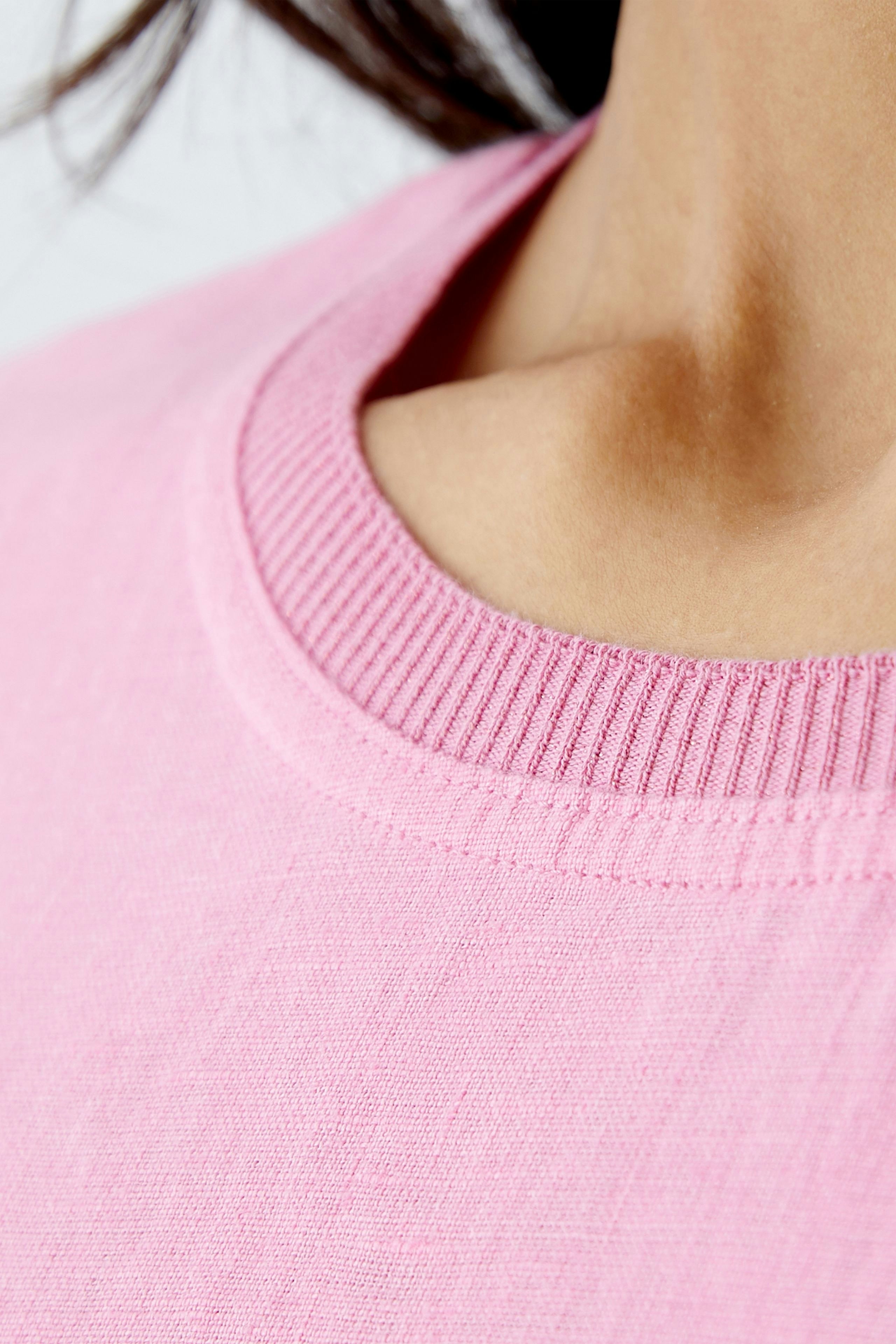 Close-up of a woman's pink dress with a round neckline, showcasing its soft fabric and elegant design.
