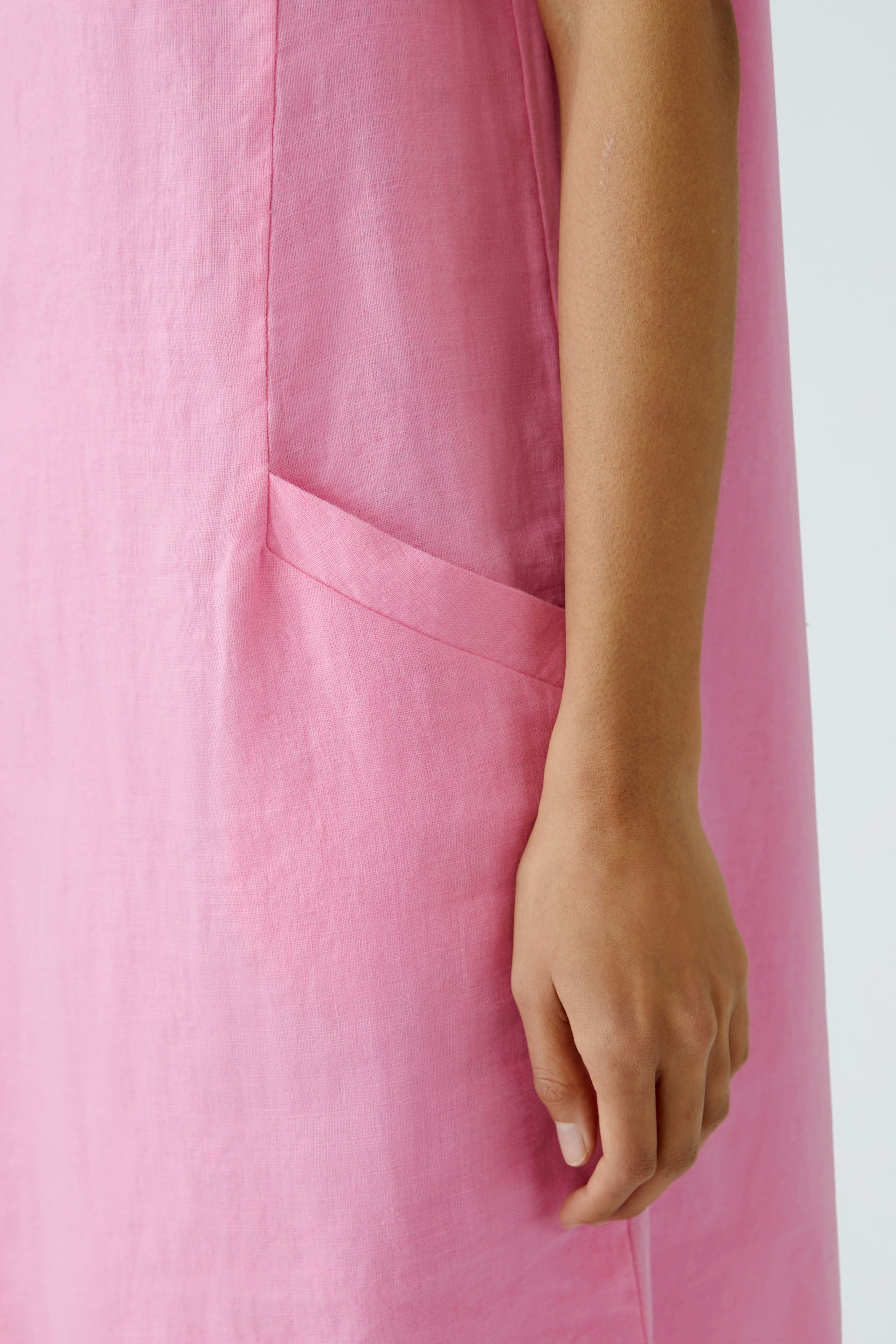 Elegant pink dress: A woman showcases a stylish, lightweight dress with pockets, perfect for warm days.