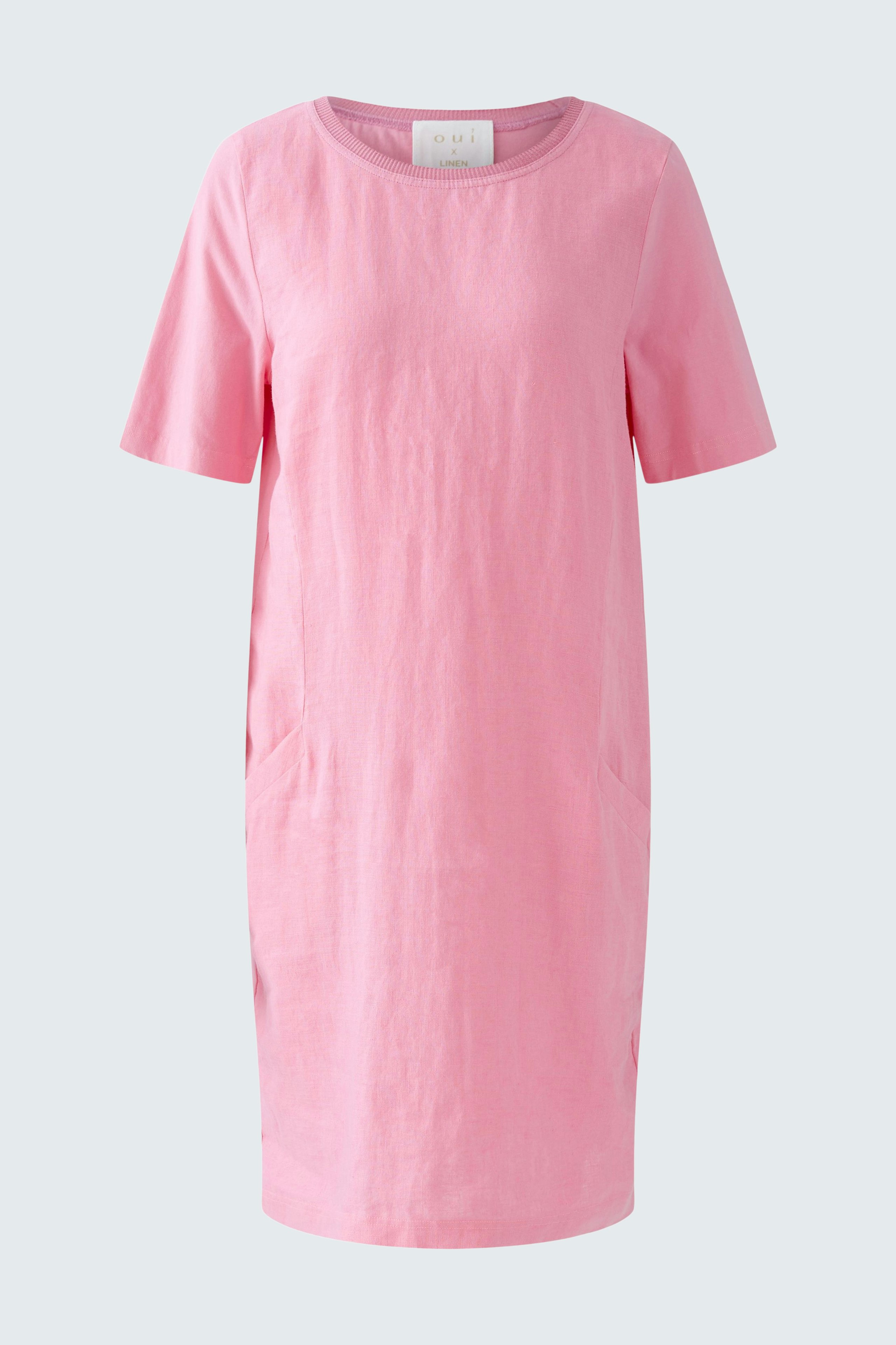 Casual pink dress: A woman in a short-sleeved, relaxed-fit dress with side pockets.