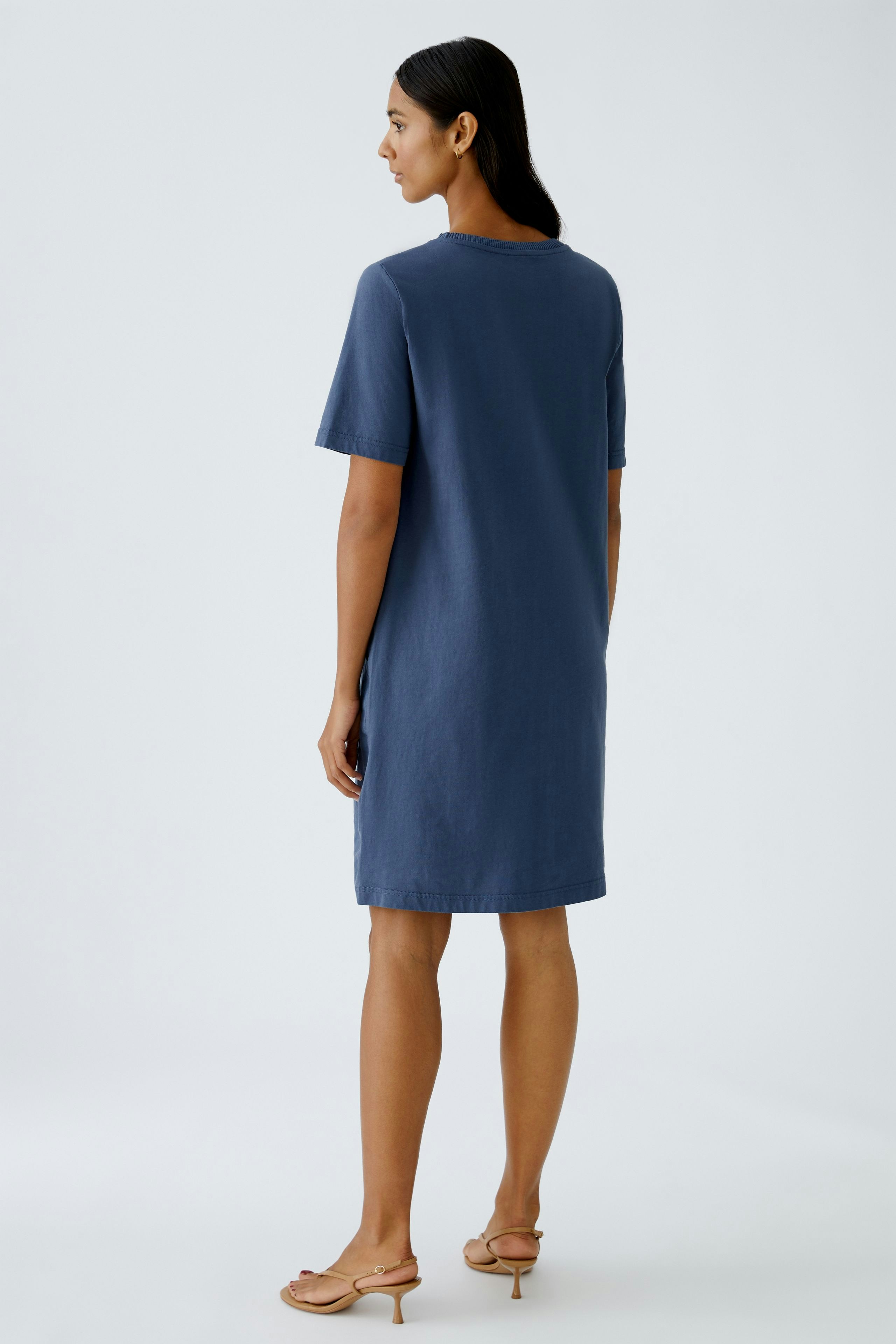 Casual women's dress: A woman in a blue short-sleeve dress stands confidently, showcasing a relaxed fit.