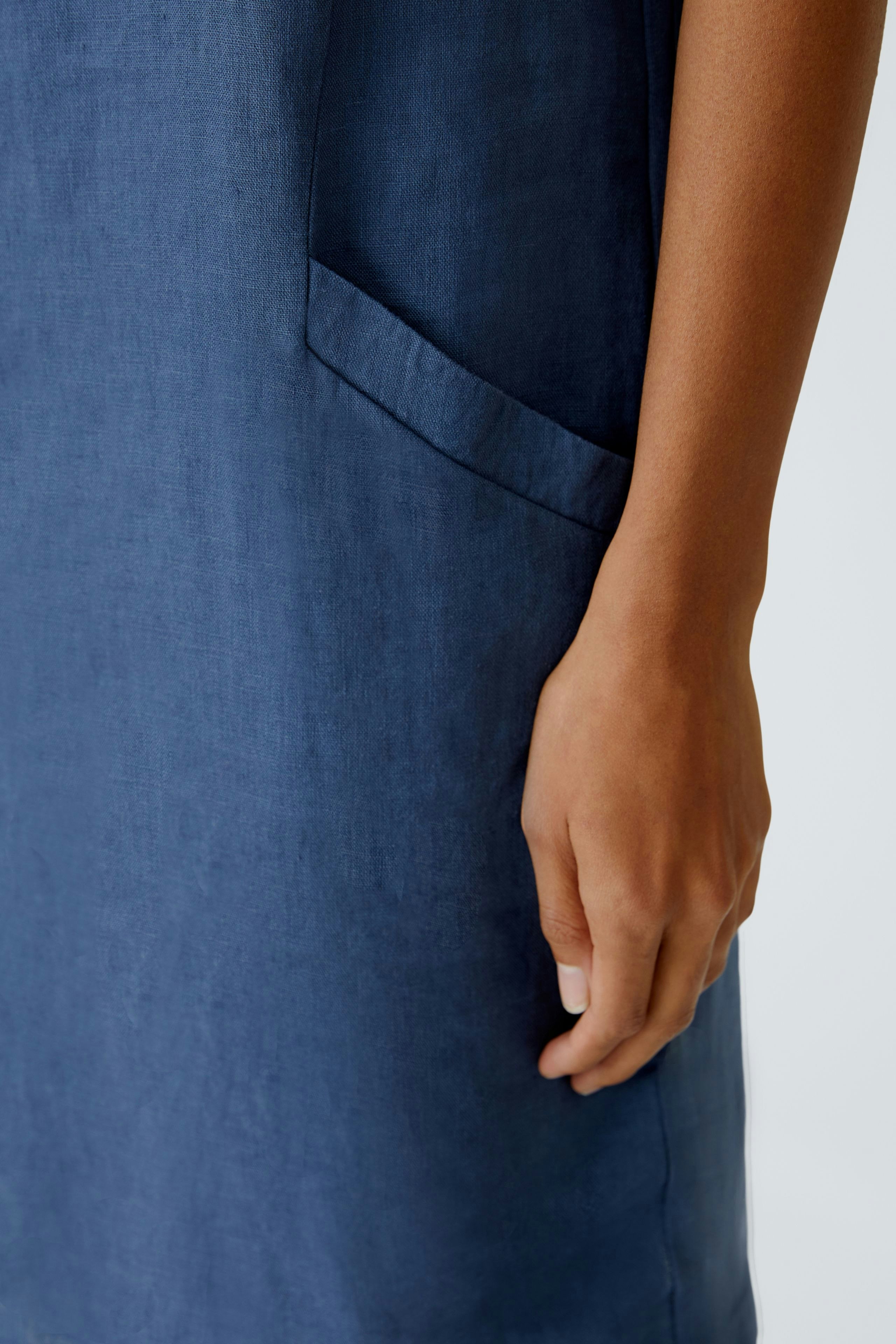 Casual women's dress: Close-up of a woman's hand on a blue dress with a pocket.