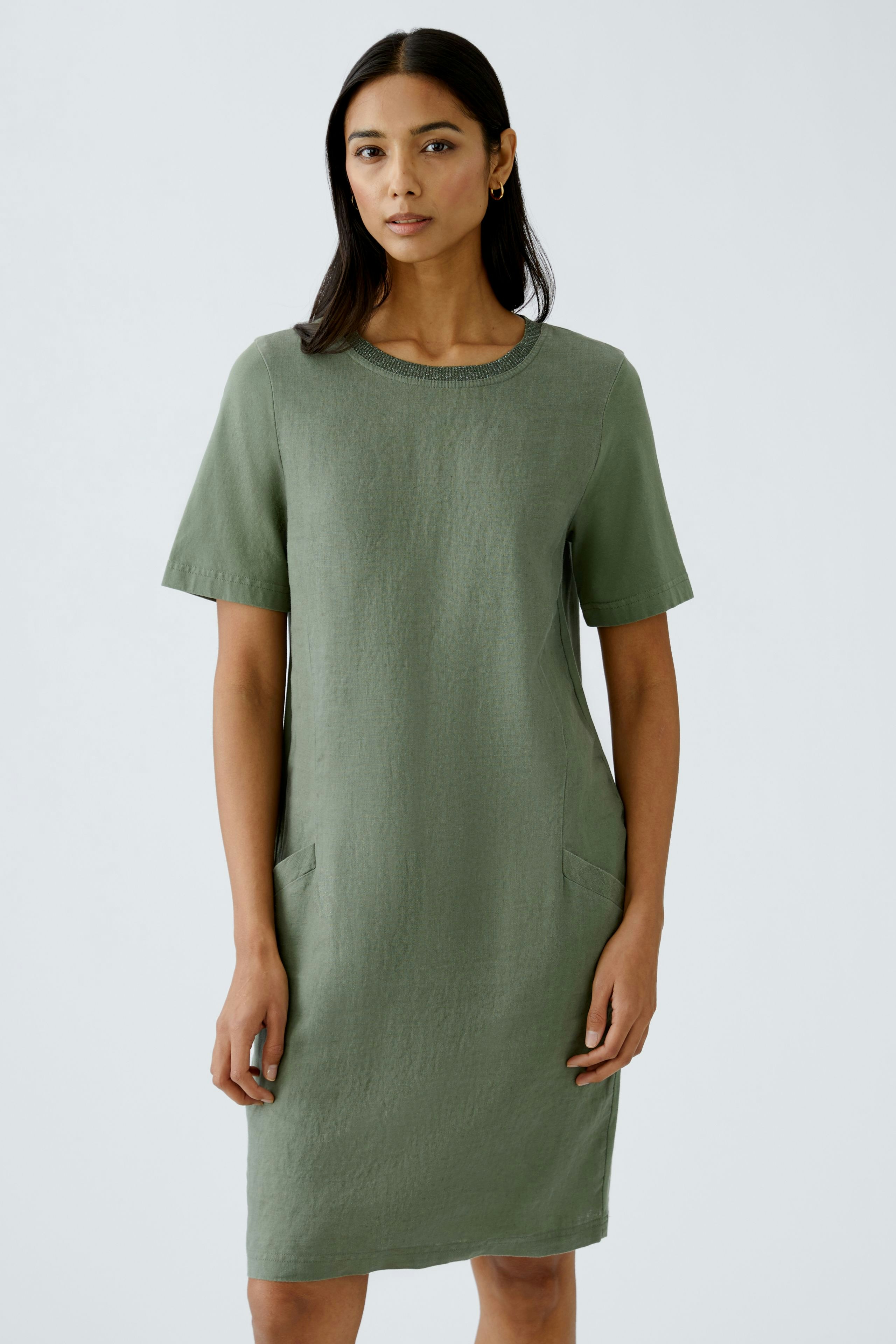 Casual women's dress: A woman in a short-sleeved, green dress with pockets, exuding effortless style.
